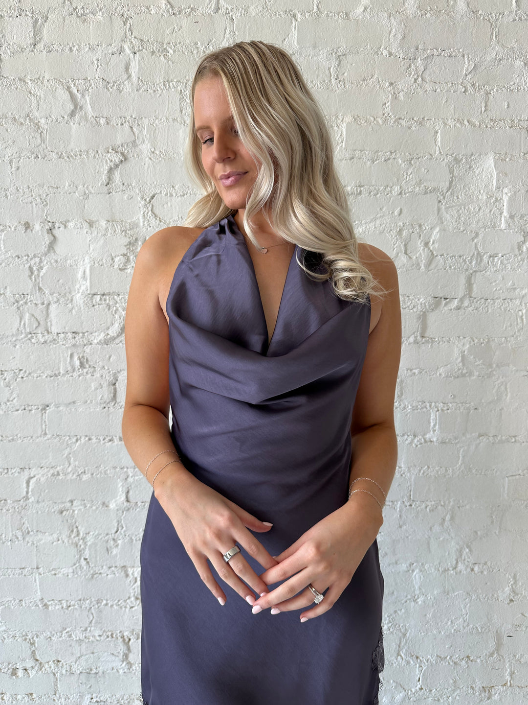 Woman wearing purple satin lace trim midi dress with self tie cowl halter neck. 