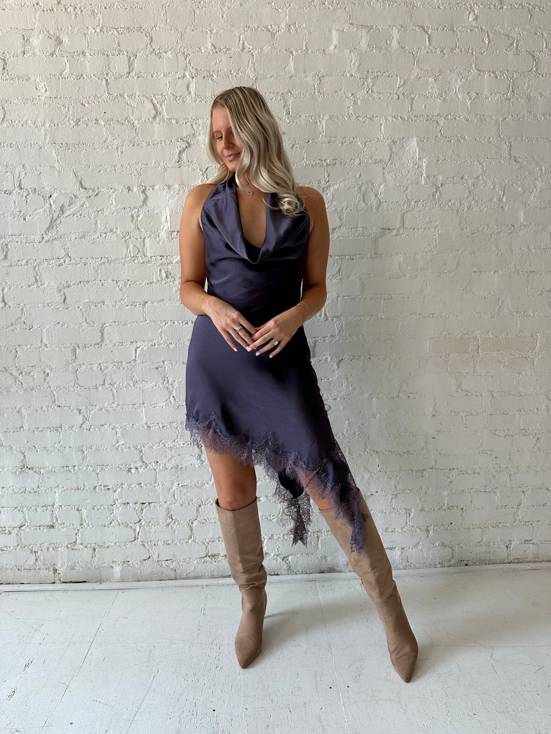 Woman wearing purple satin lace trim midi dress with self tie cowl halter neck. 