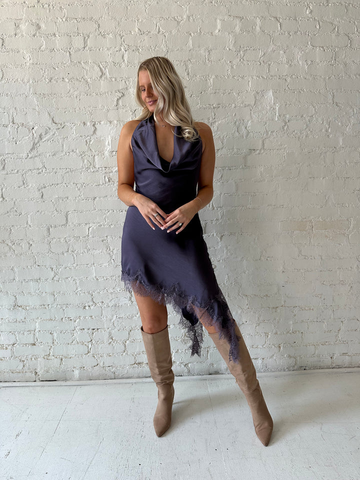 Woman wearing purple satin lace trim midi dress with self tie cowl halter neck. 