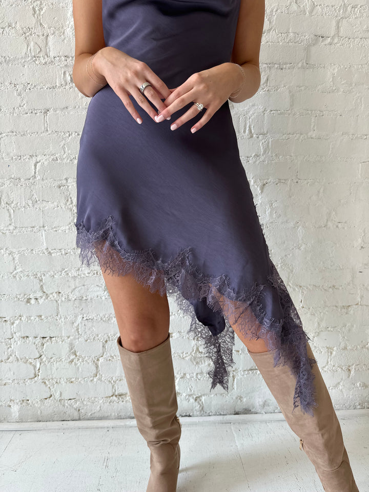 Woman wearing purple satin lace trim midi dress with self tie cowl halter neck. 