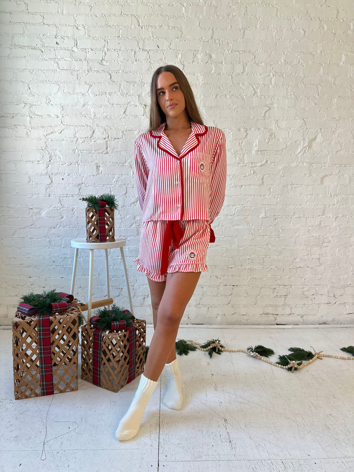 Woman wearing red and white striped pajama set with red velvet trim.