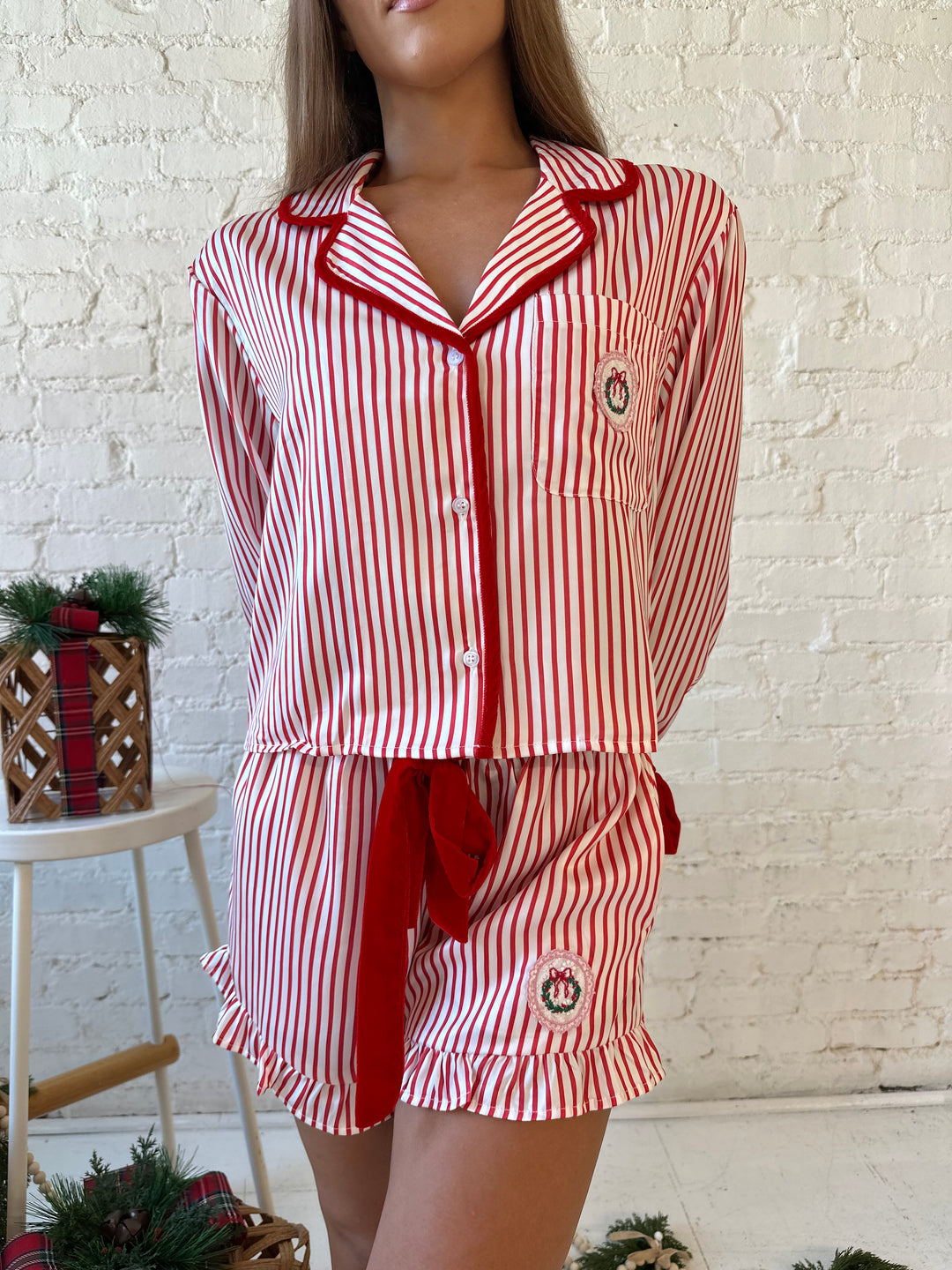 Woman wearing red and white striped pajama set with red velvet trim.