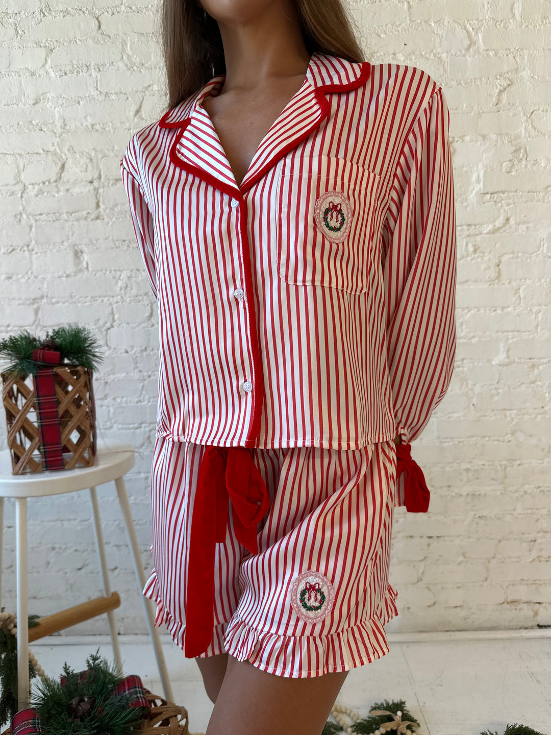 Woman wearing red and white striped pajama set with red velvet trim.