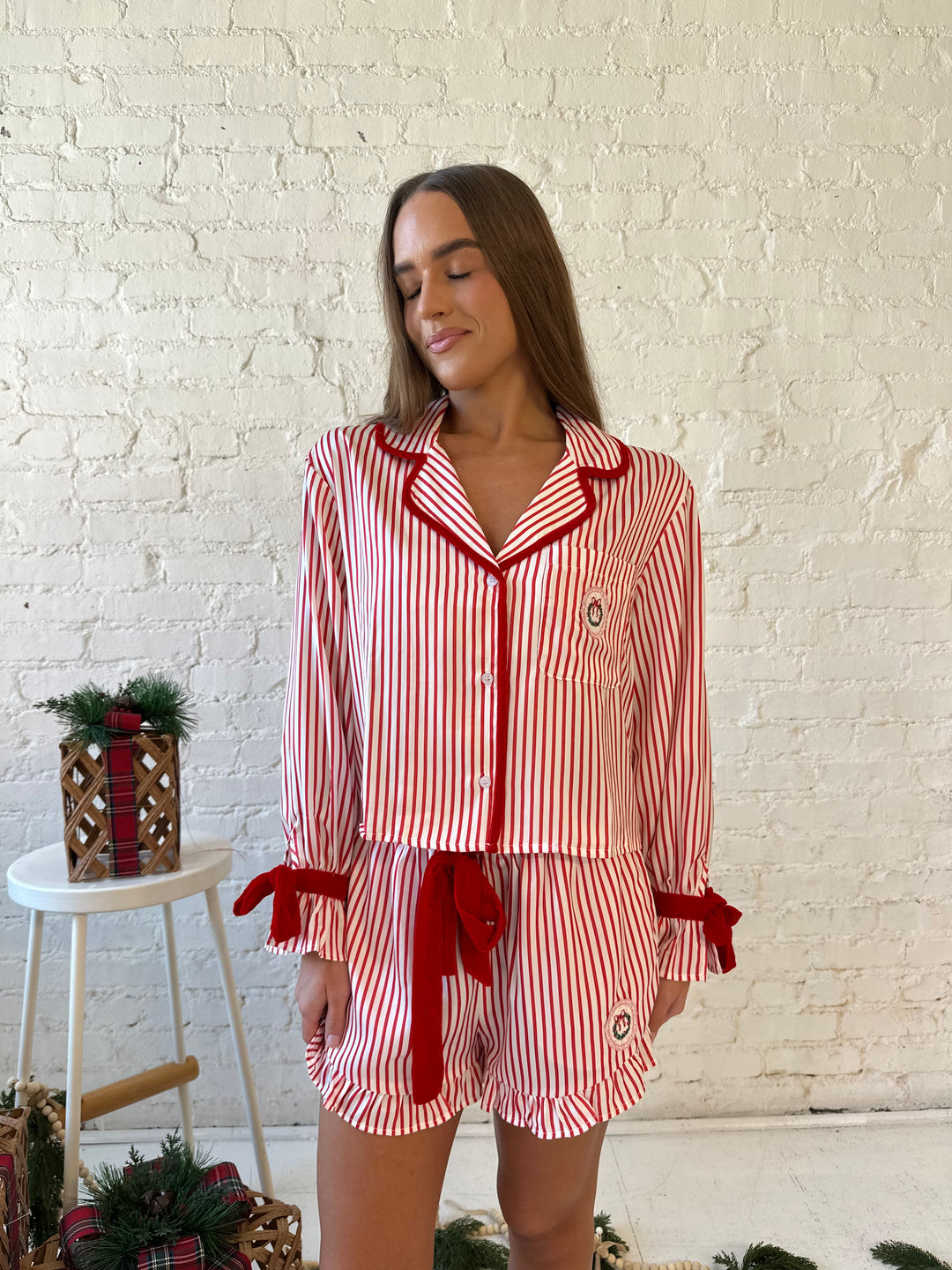 Woman wearing red and white striped pajama set with red velvet trim.