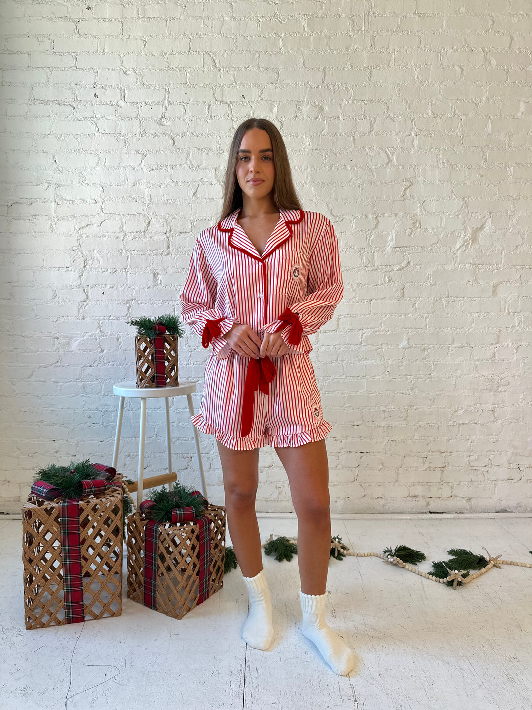 Woman wearing red and white striped pajama set with red velvet trim.