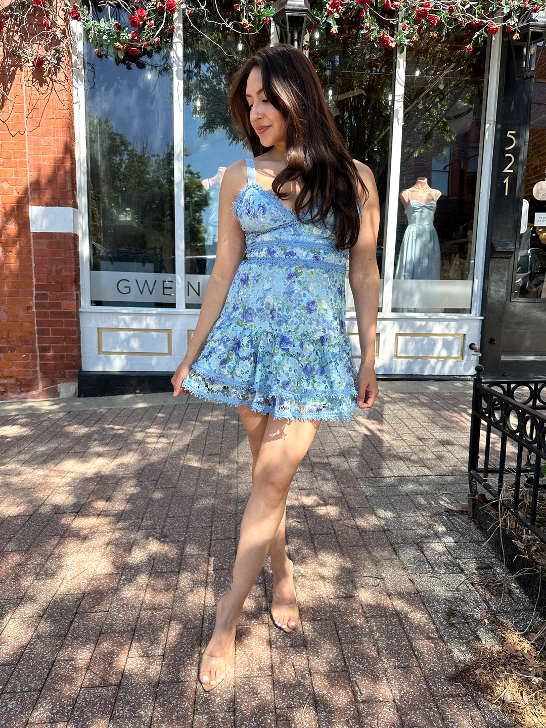 Woman wearing blue textured floral mini dress with tiered bottom, and adjustable straps.