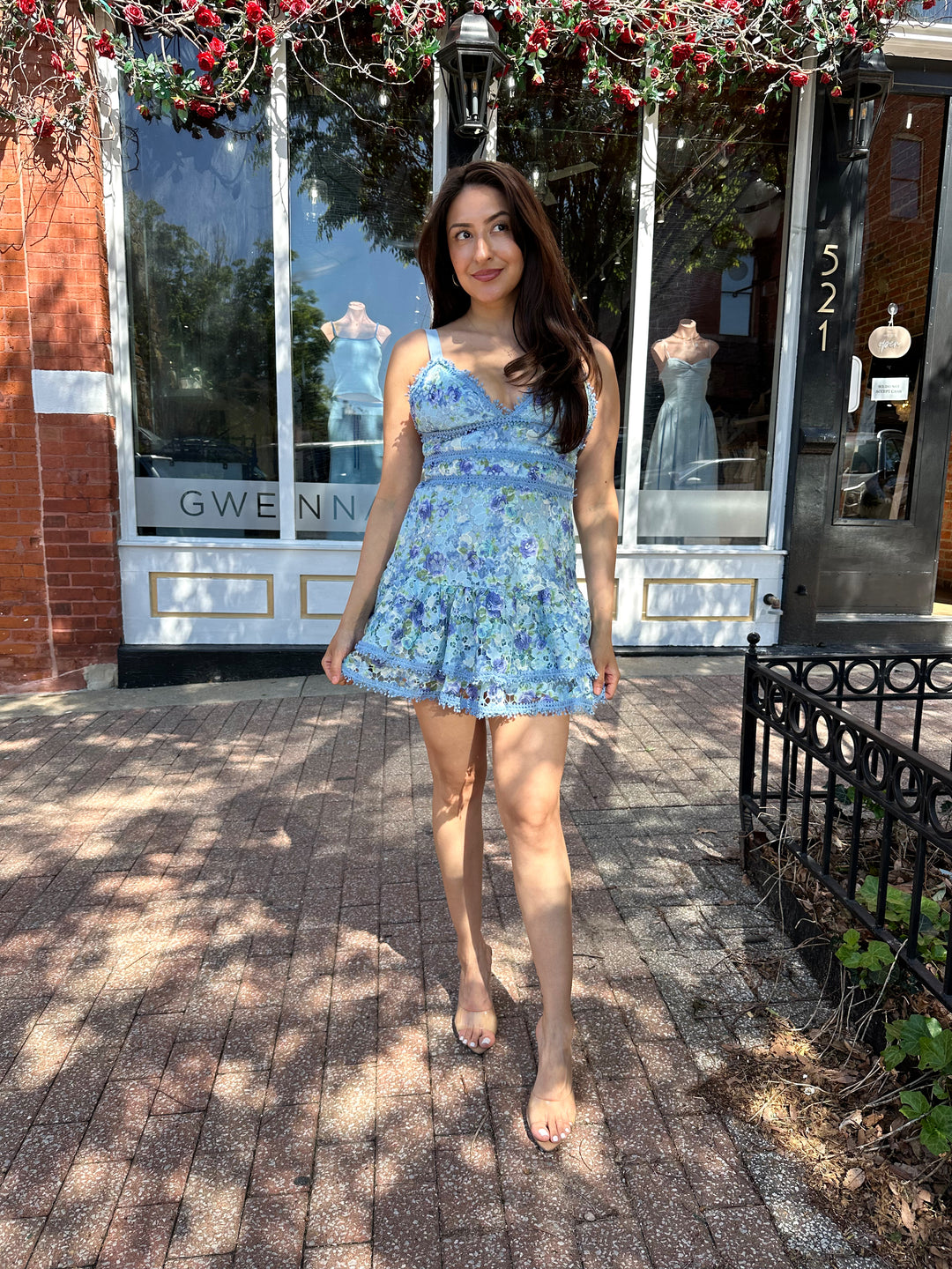 Woman wearing blue textured floral mini dress with tiered bottom, and adjustable straps.
