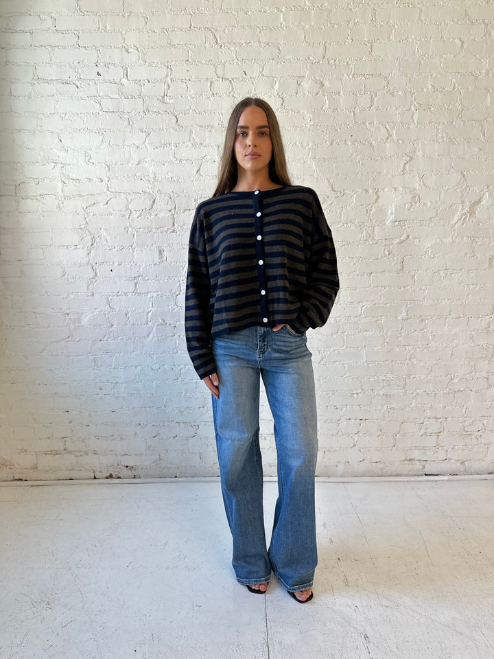Woman wearing navy and taupe striped button down cardigan with medium wash jeans.