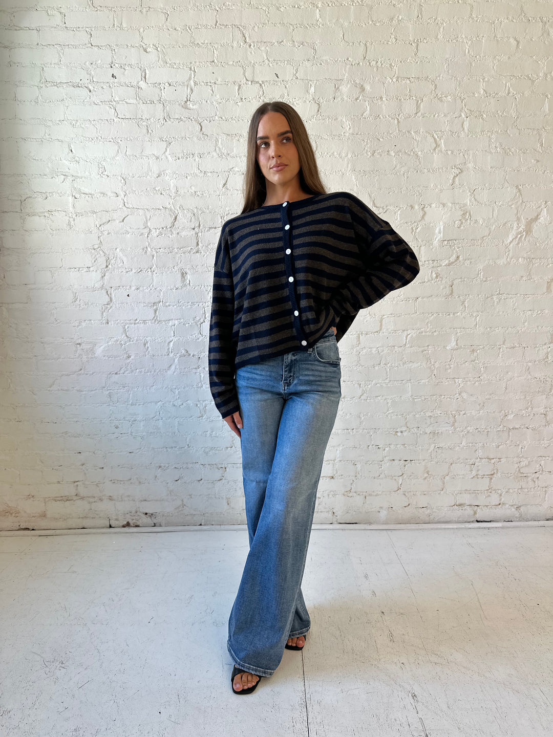 Woman wearing navy and taupe striped button down cardigan with medium wash jeans.