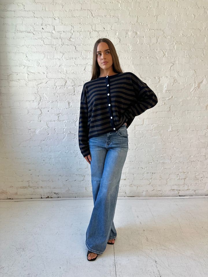 Woman wearing navy and taupe striped button down cardigan with medium wash jeans.