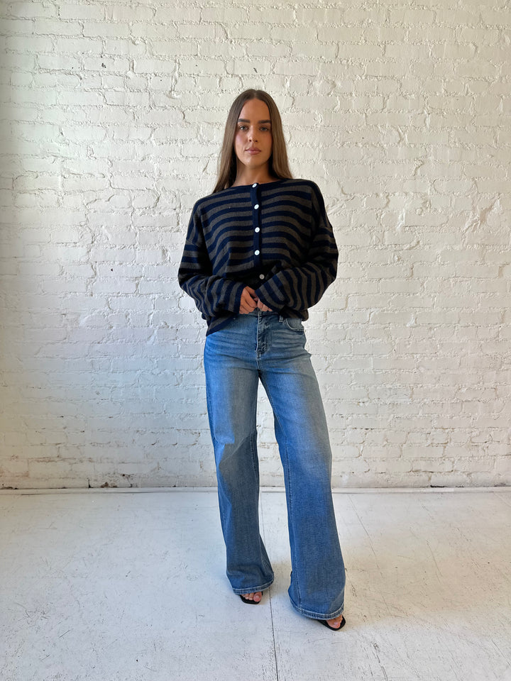 Woman wearing navy and taupe striped button down cardigan with medium wash jeans.