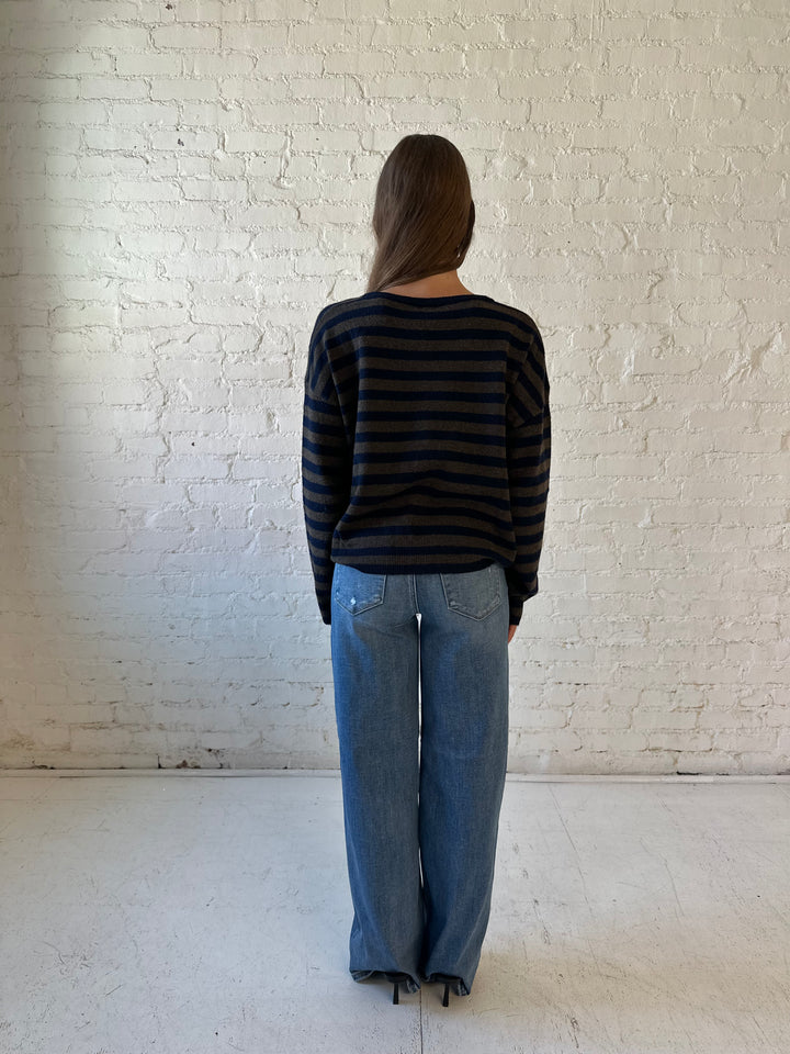 Woman wearing navy and taupe striped button down cardigan with medium wash jeans.