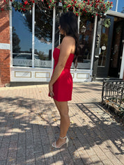 Woman wearing red strapless tailored mini dress with built in shorts. 