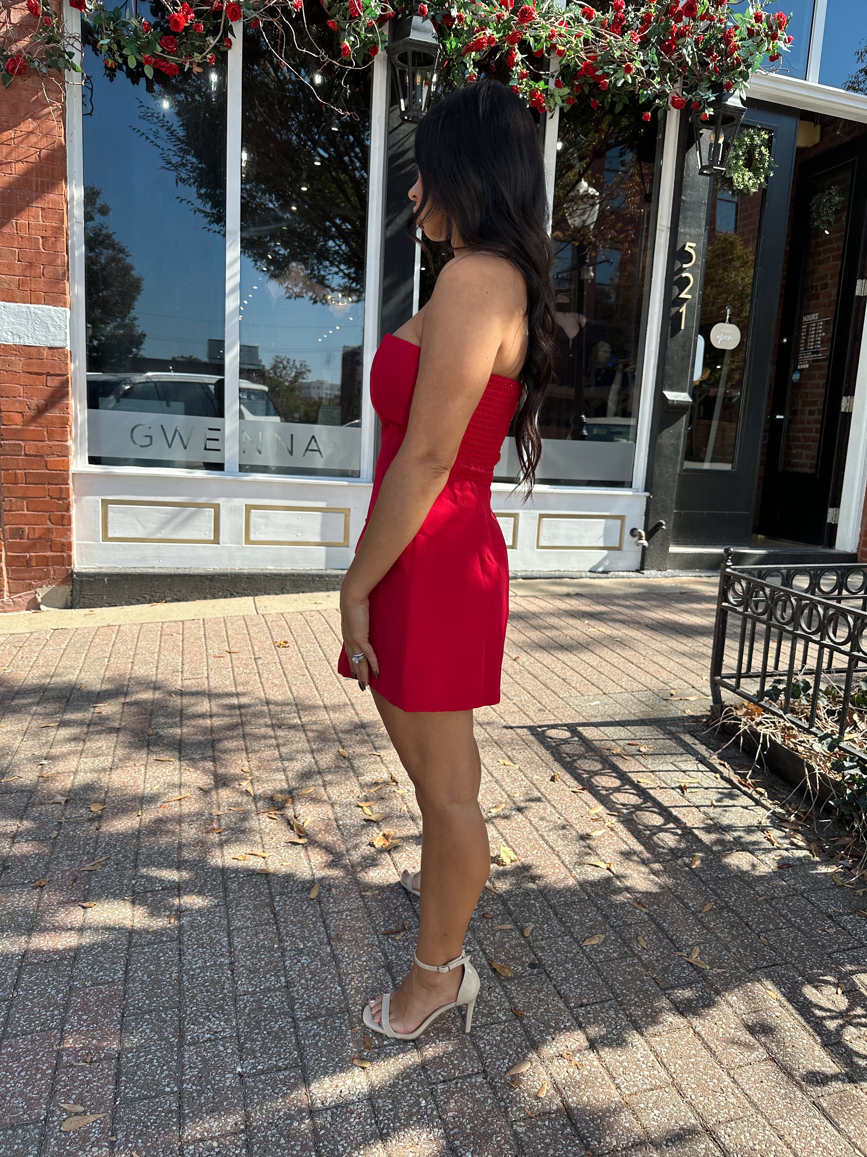 Woman wearing red strapless tailored mini dress with built in shorts. 
