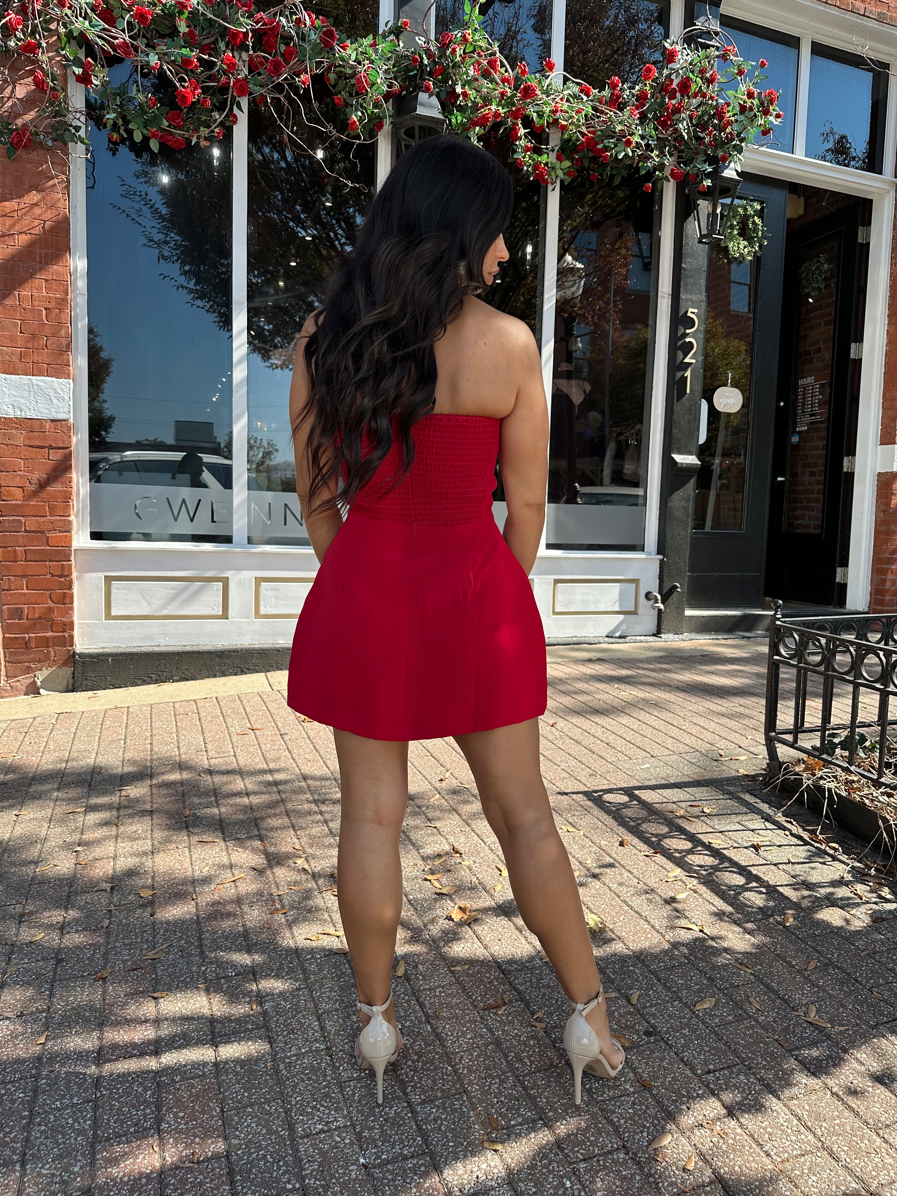 Woman wearing red strapless tailored mini dress with built in shorts. 