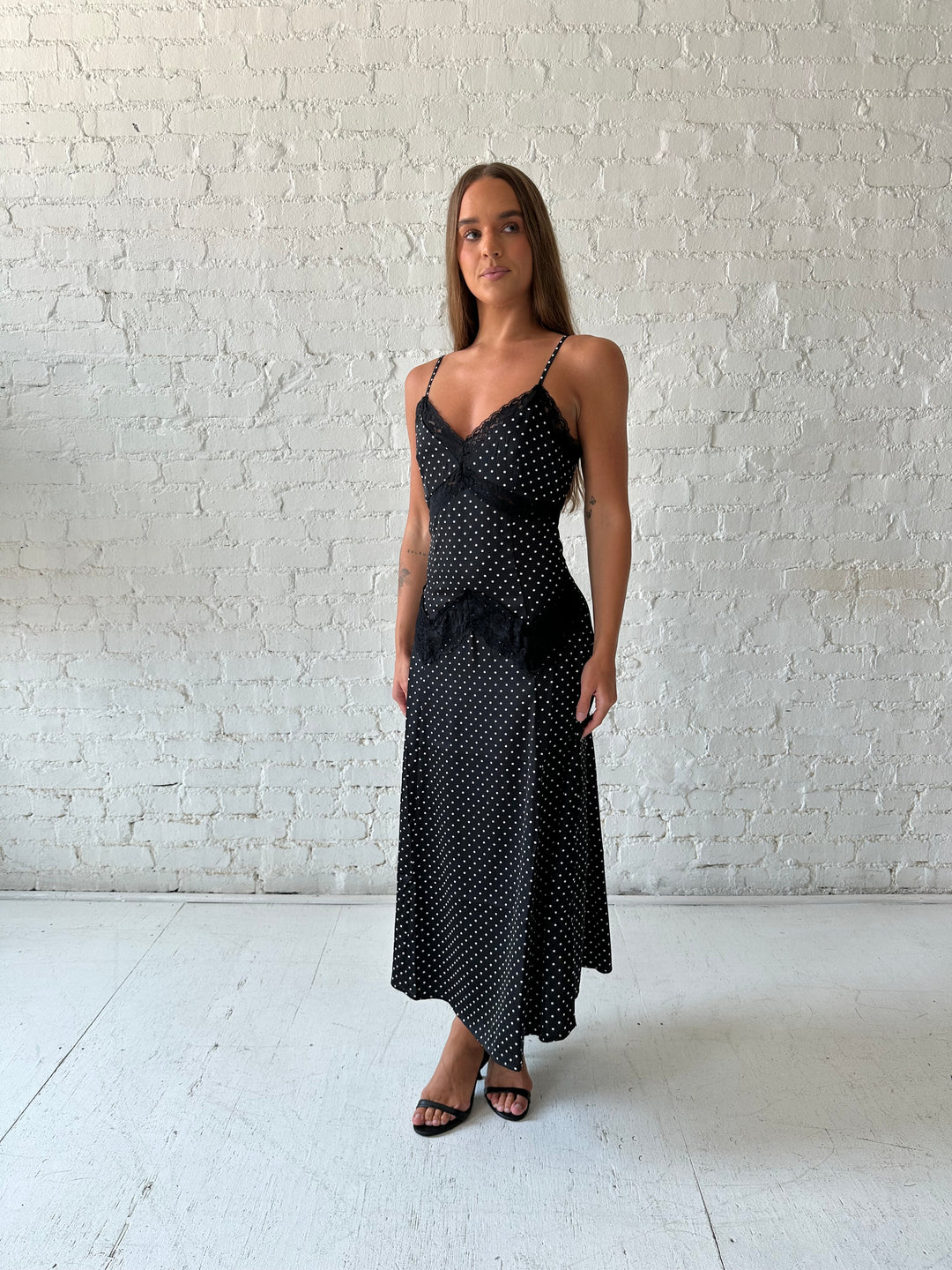 Woman wearing black polka dot satin maxi dress with lace trim detail.
