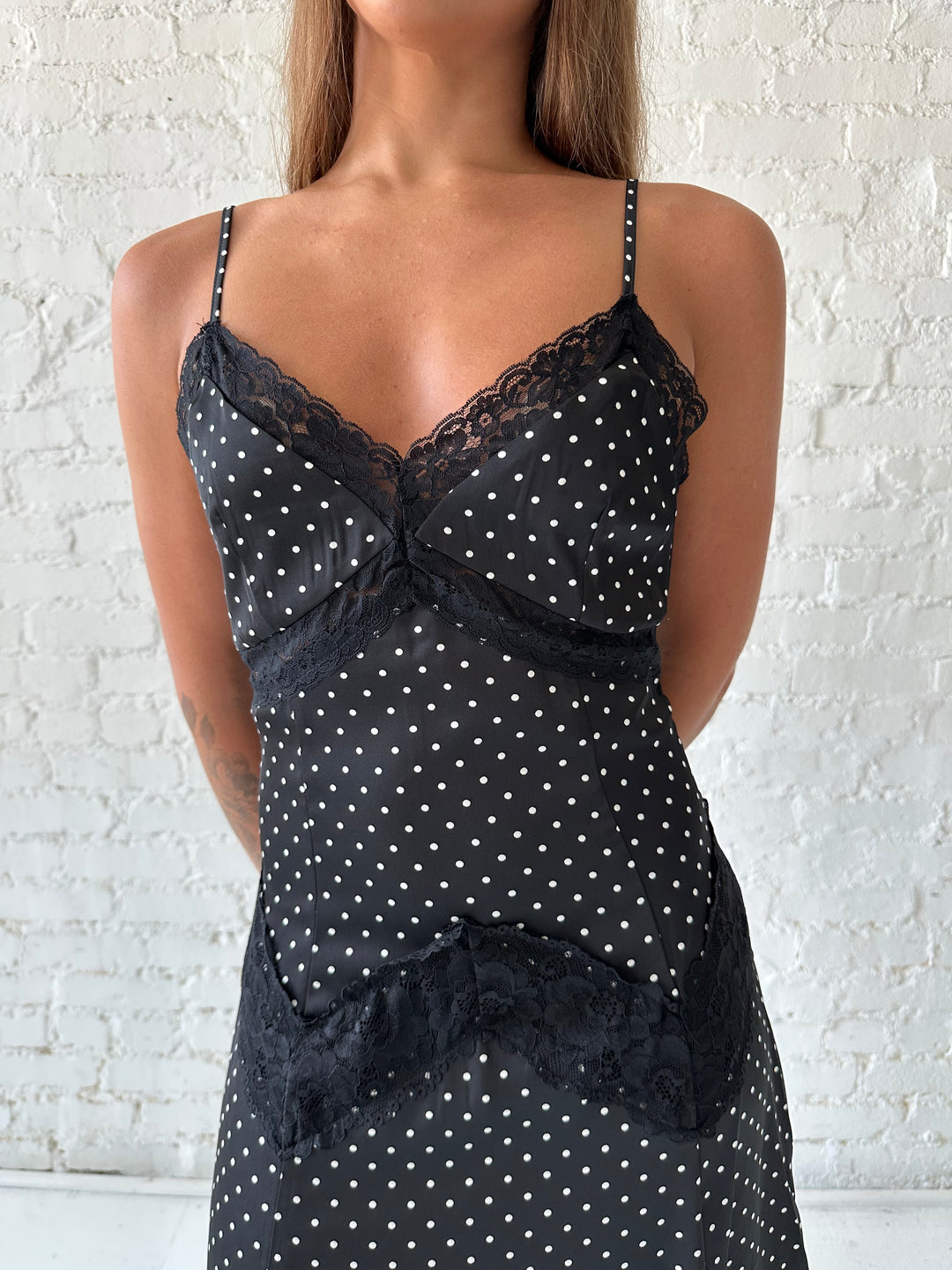 Woman wearing black polka dot satin maxi dress with lace trim detail.