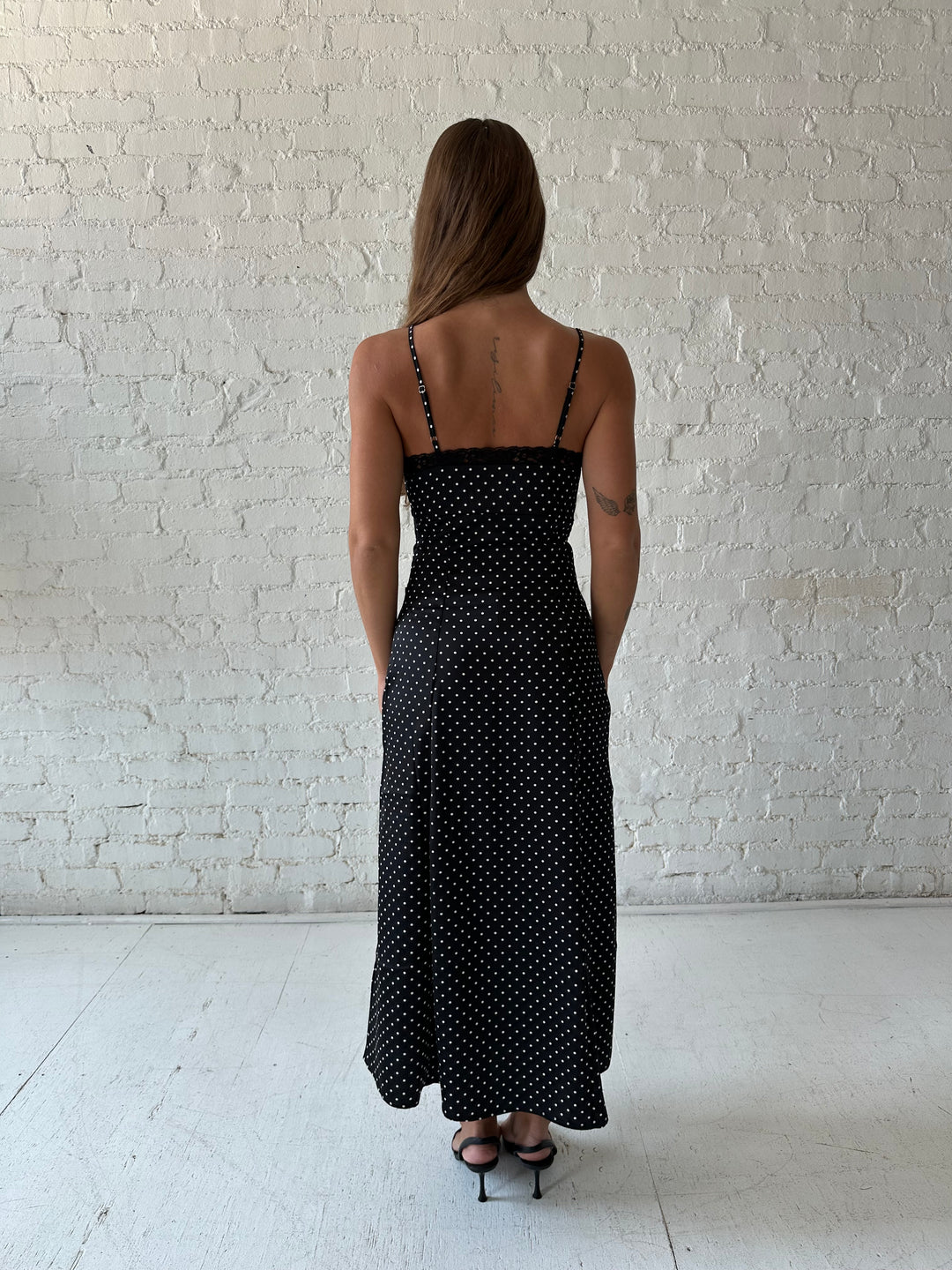 Woman wearing black polka dot satin maxi dress with lace trim detail.