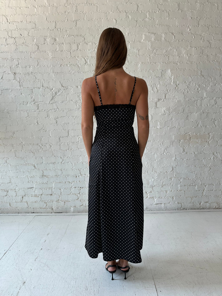 Woman wearing black polka dot satin maxi dress with lace trim detail.