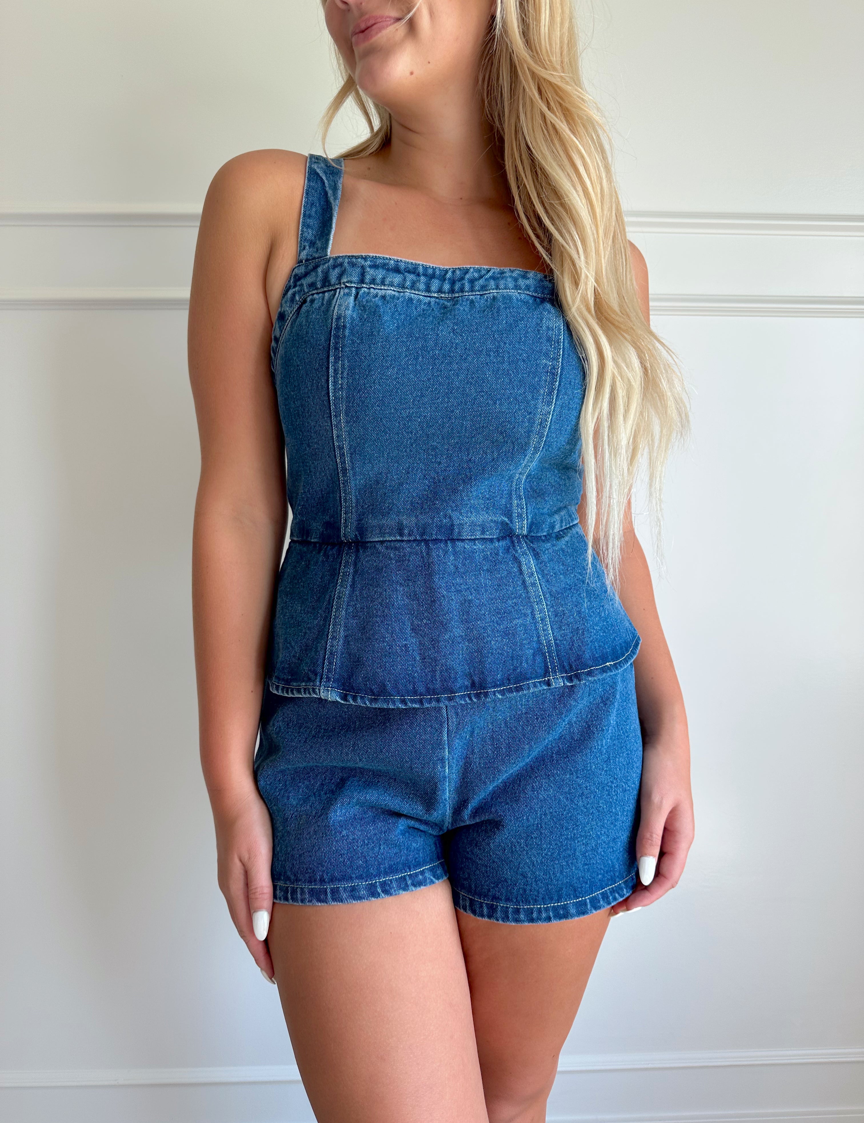 Dark wash denim peplum romper with self tie back closure.