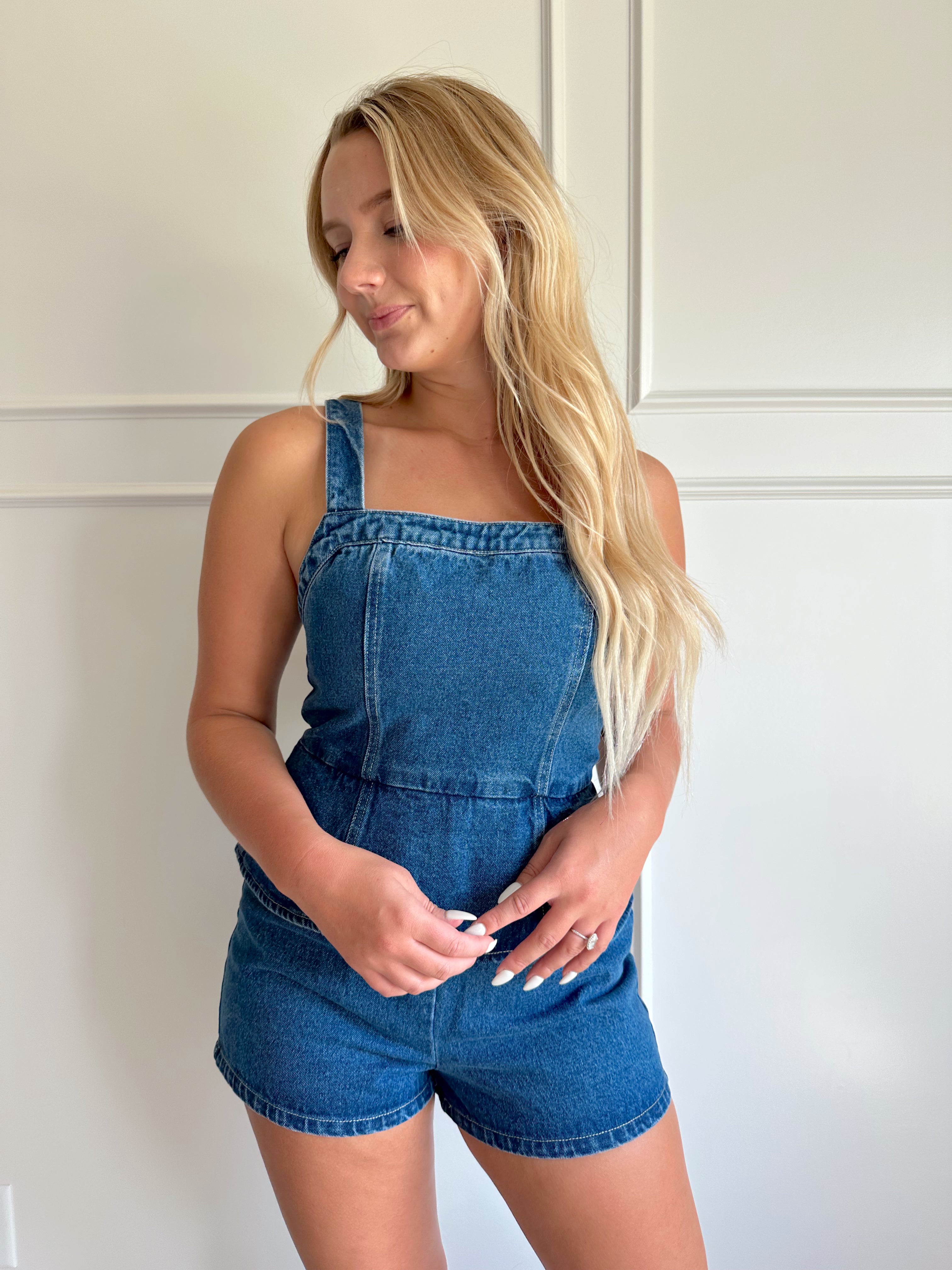 Dark wash denim peplum romper with self tie back closure.