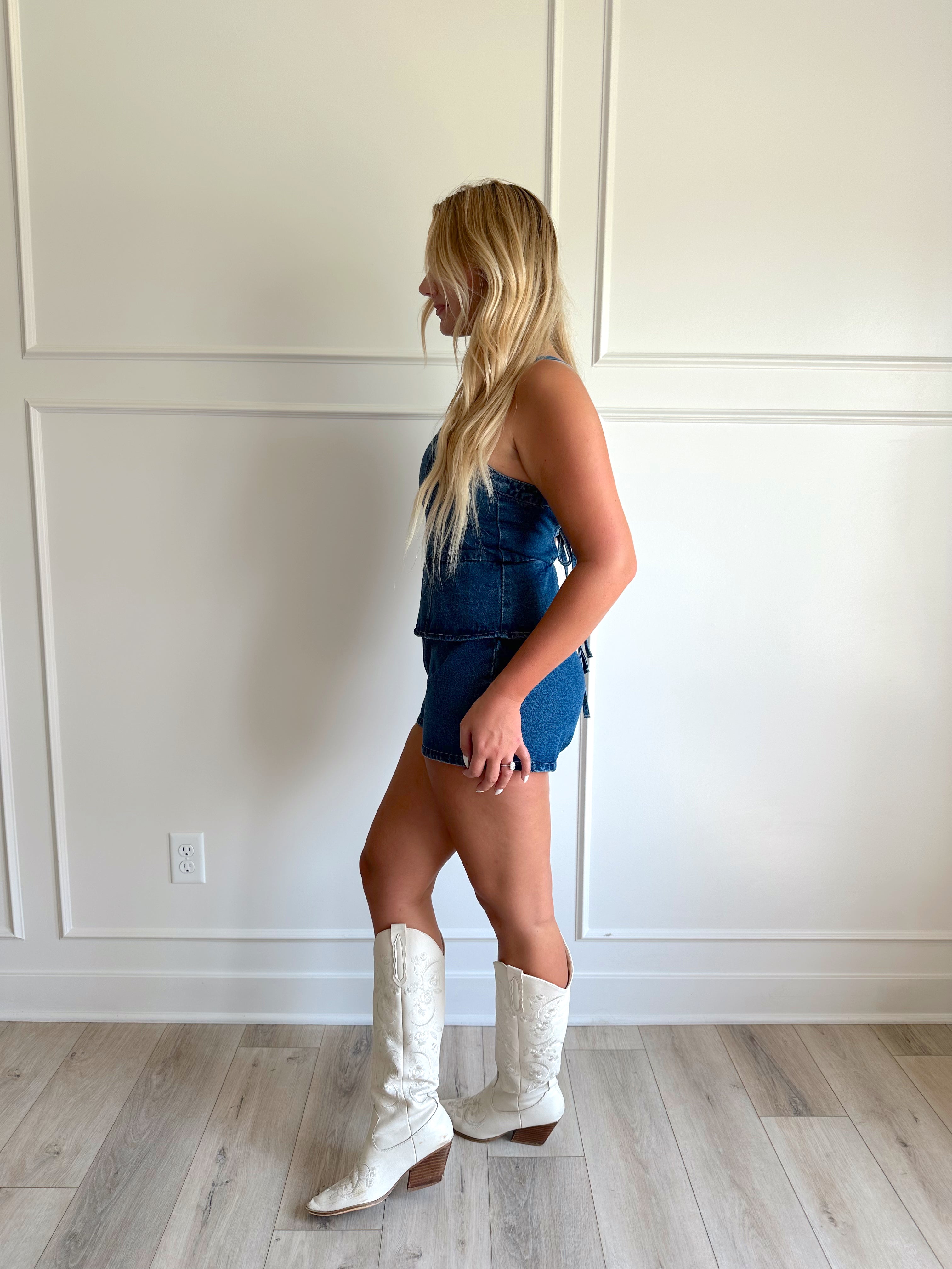Dark wash denim peplum romper with self tie back closure.