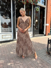 Woman wearing leopard maxi dress with v-neckline and adjustable straps.