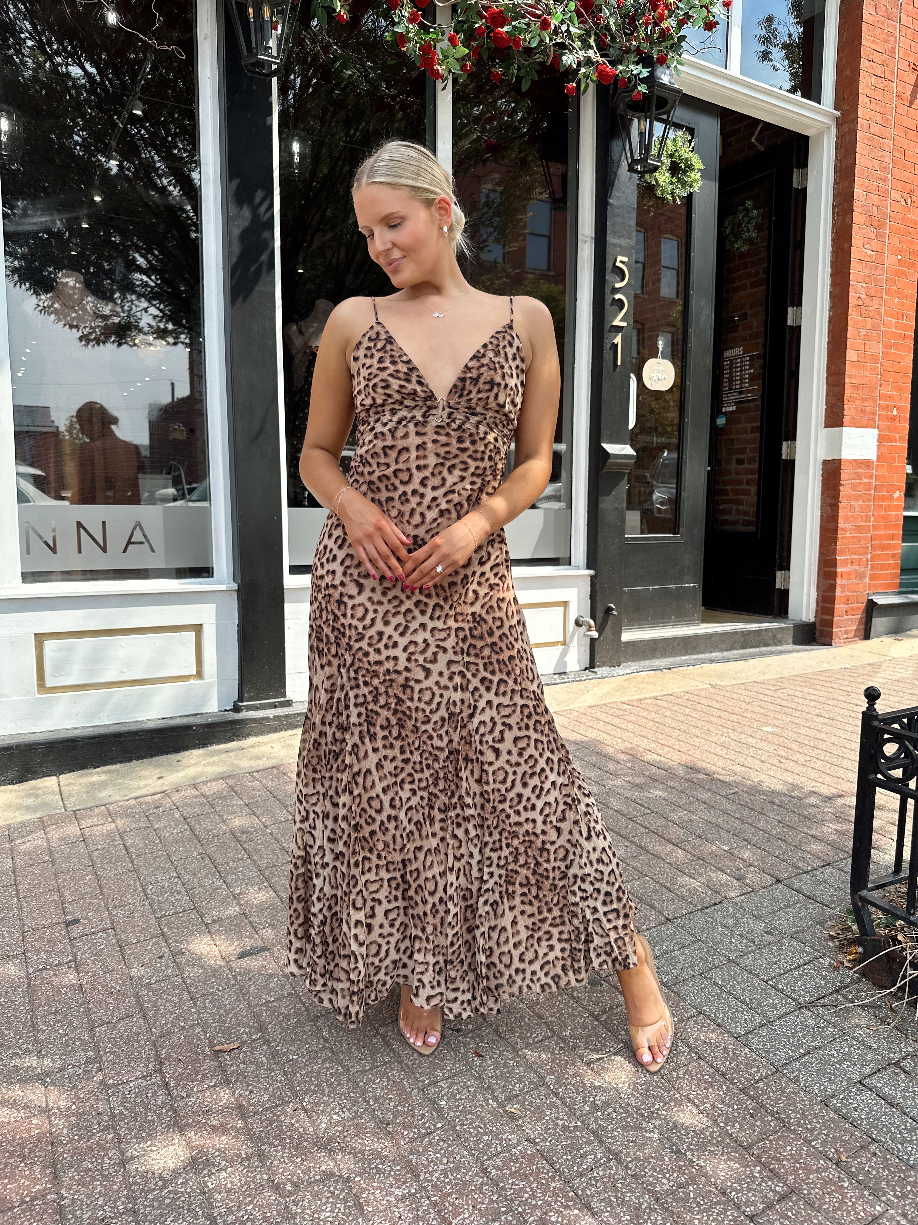 Woman wearing leopard maxi dress with v-neckline and adjustable straps.