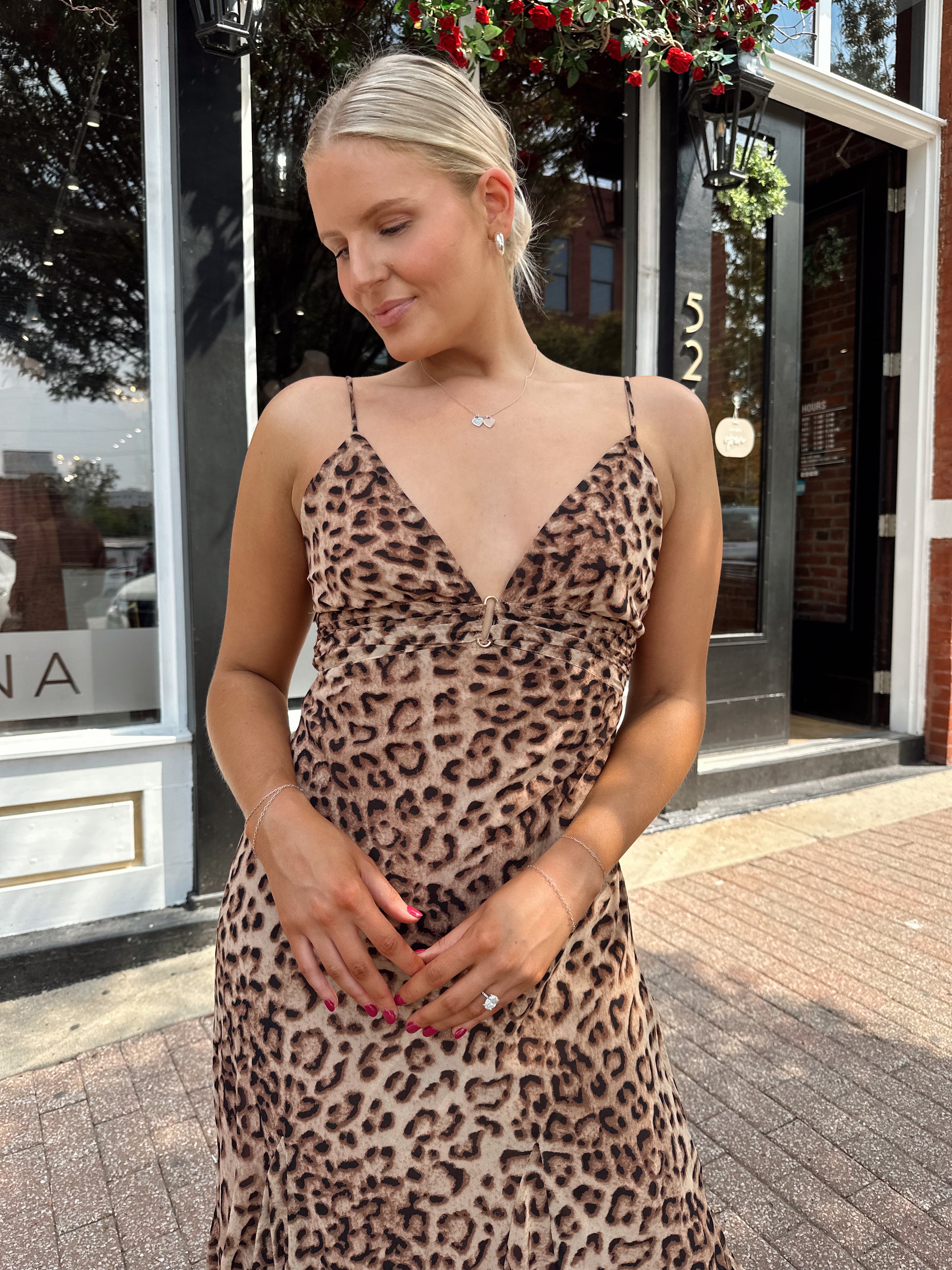 Woman wearing leopard maxi dress with v-neckline and adjustable straps.