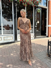 Woman wearing leopard maxi dress with v-neckline and adjustable straps.