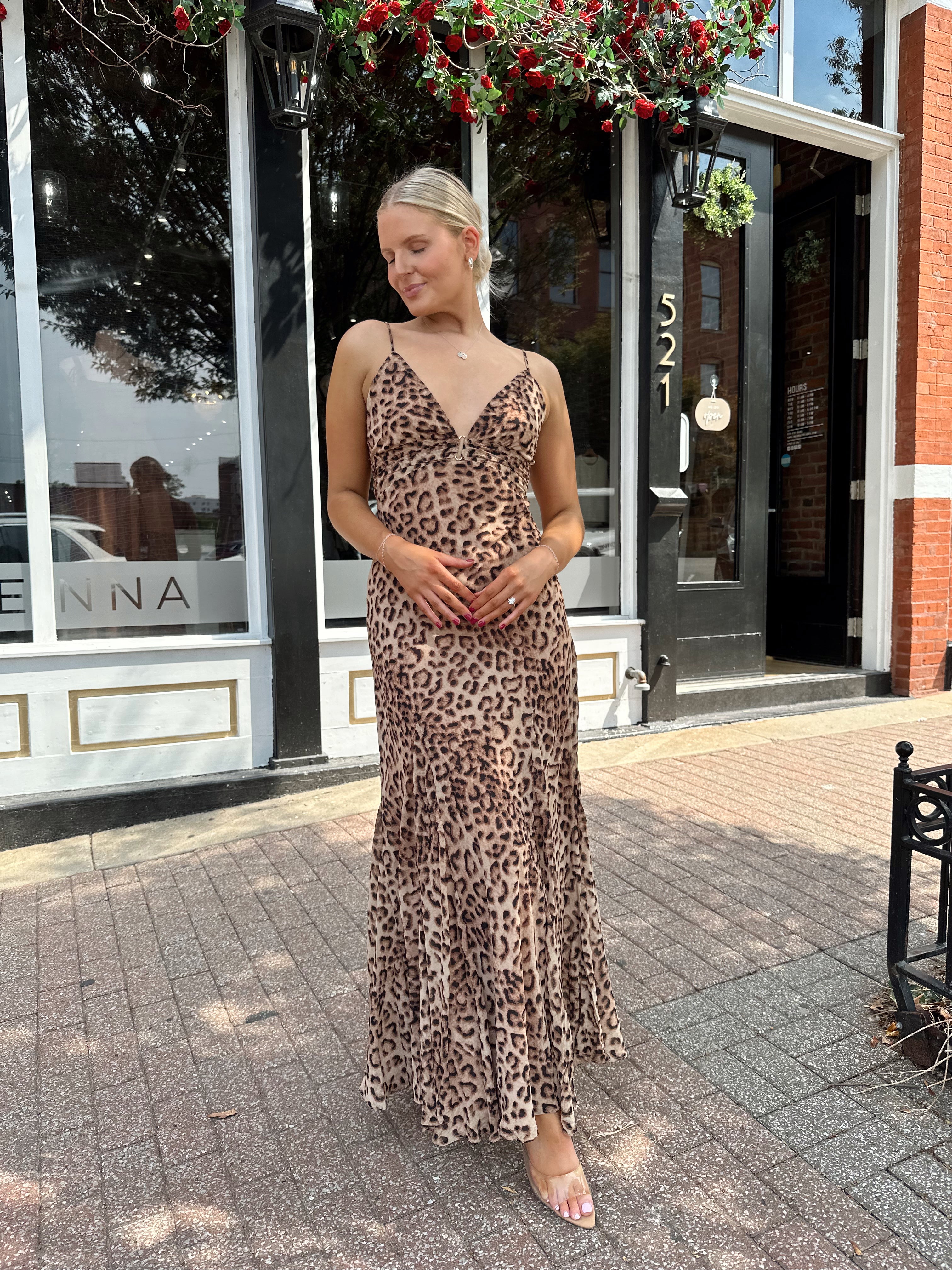 Woman wearing leopard maxi dress with v-neckline and adjustable straps.