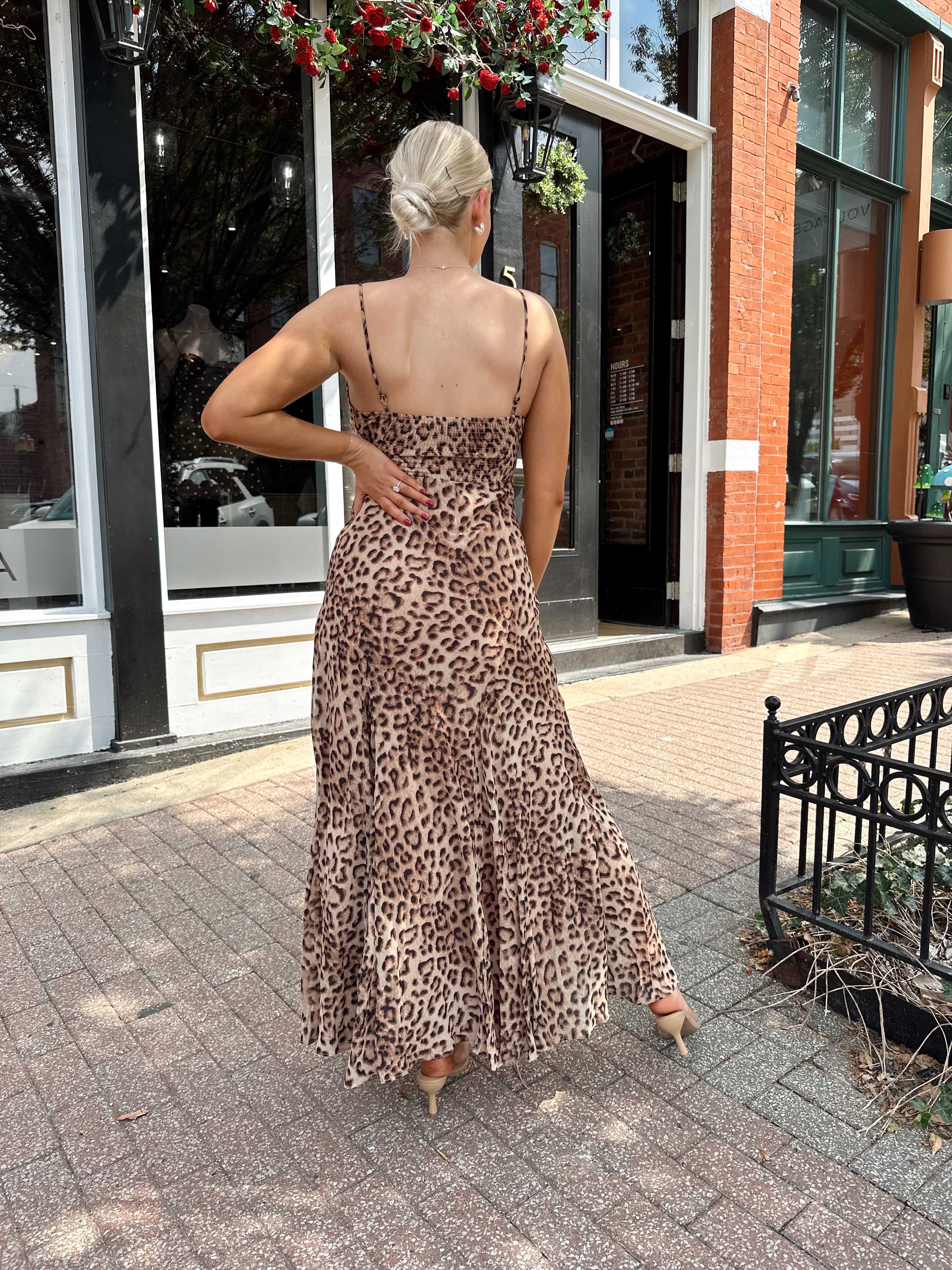 Woman wearing leopard maxi dress with v-neckline and adjustable straps.