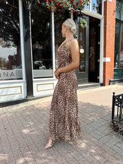 Woman wearing leopard maxi dress with v-neckline and adjustable straps.