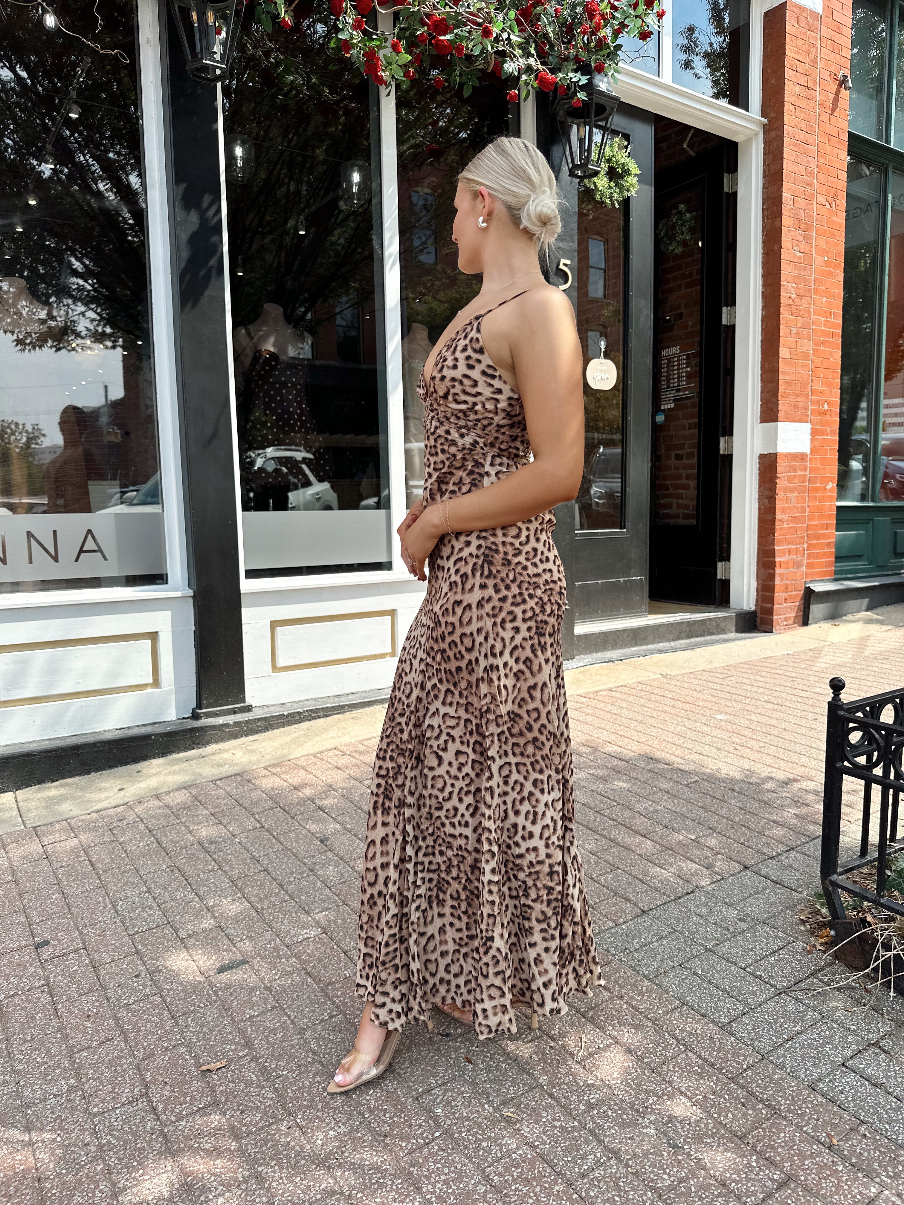Woman wearing leopard maxi dress with v-neckline and adjustable straps.
