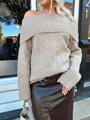 Woman wearing oversized, off the shoulder, tan sweater with brown leather skirt.