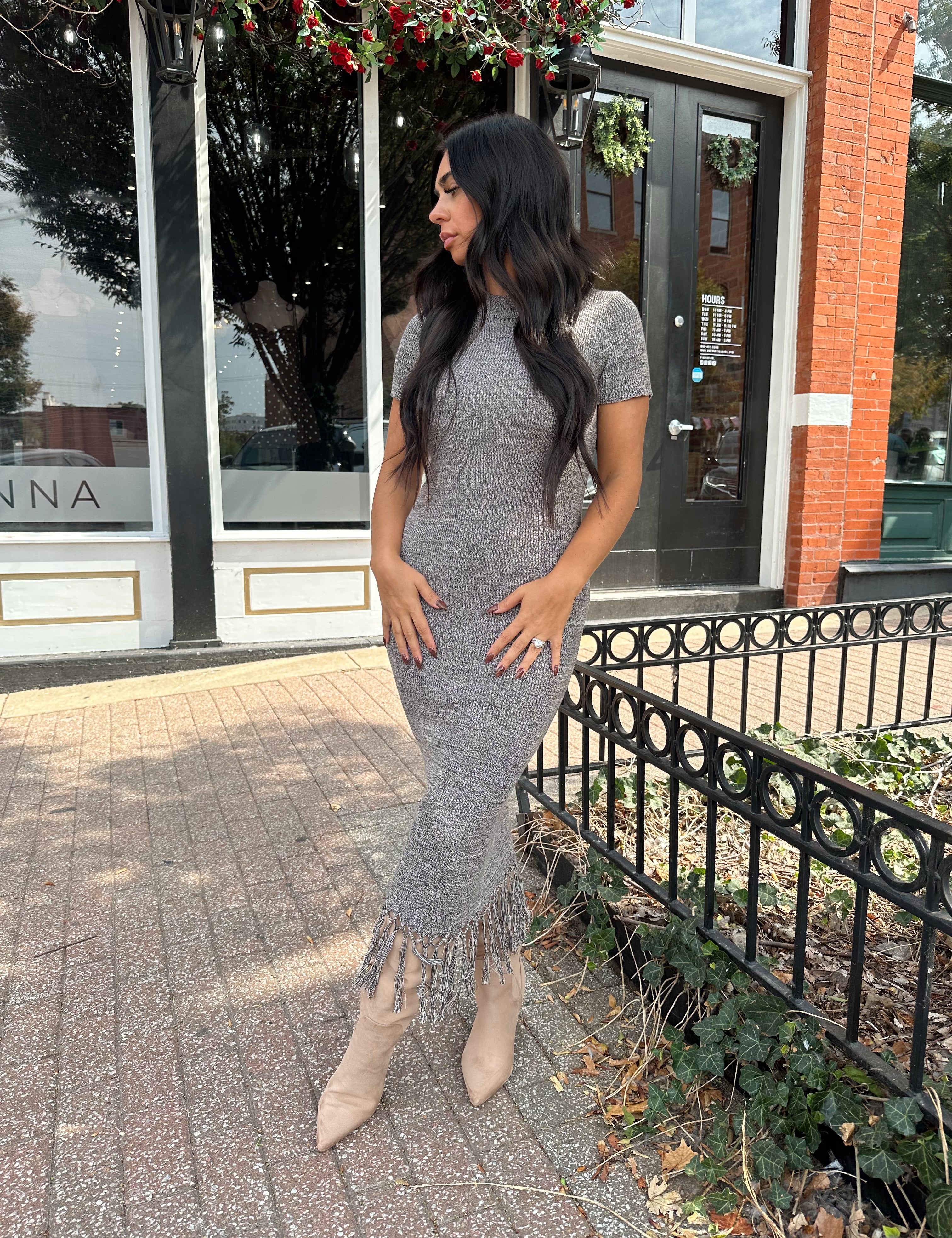 Woman wearing charcoal grey midi dress with fringe hem bottom and short sleeves.