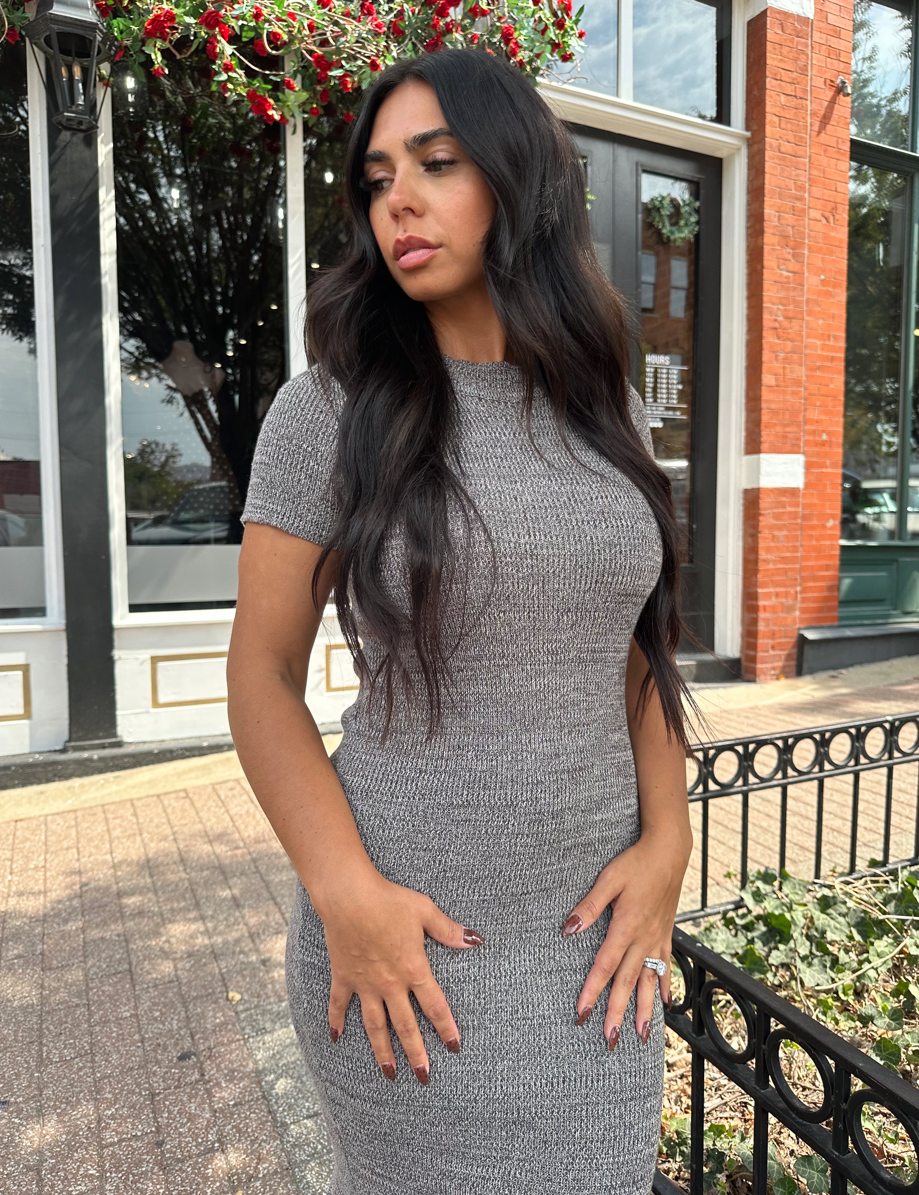 Woman wearing charcoal grey midi dress with fringe hem bottom and short sleeves.