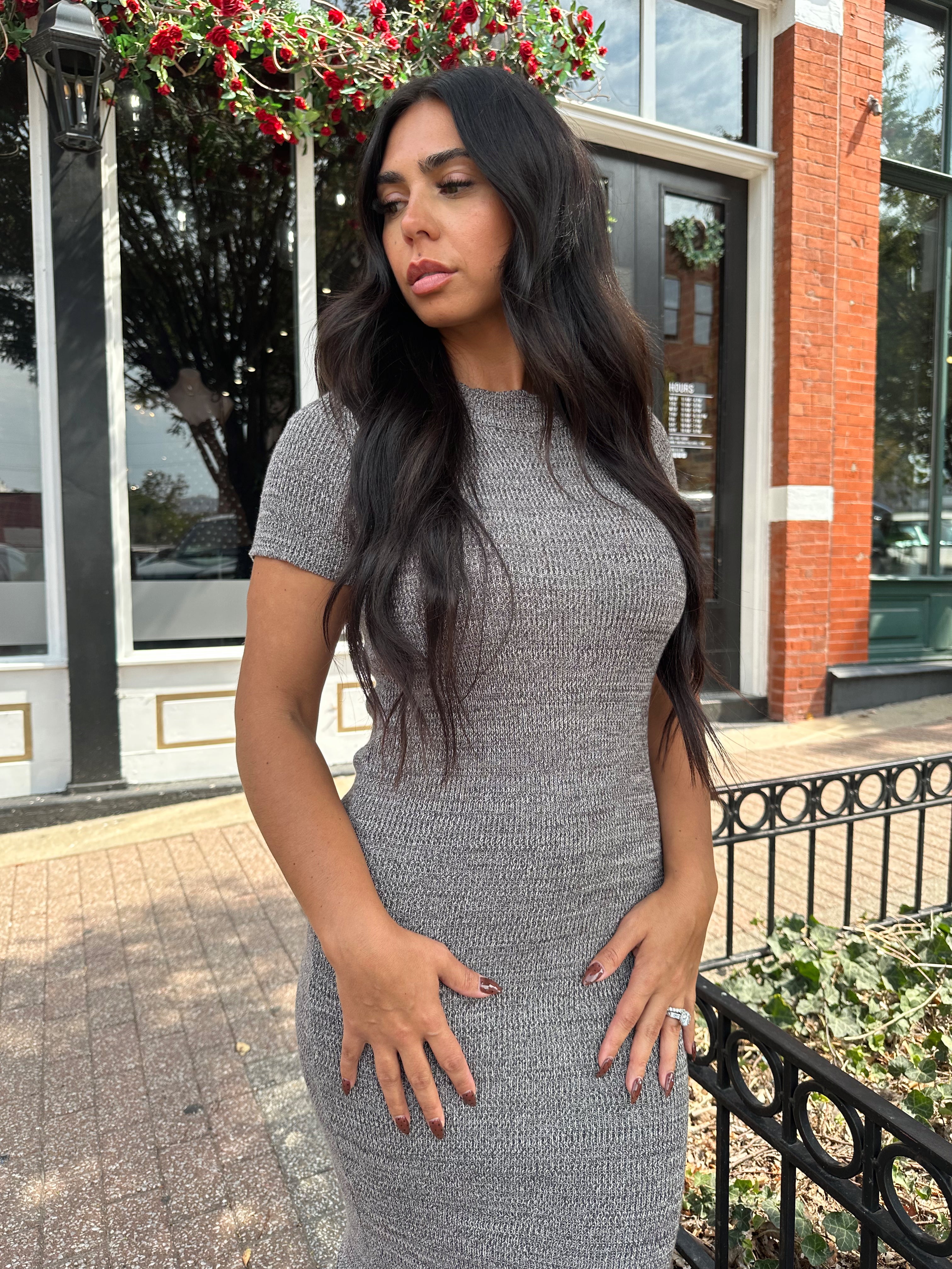 Woman wearing charcoal grey midi dress with fringe hem bottom and short sleeves.