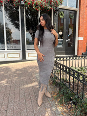 Woman wearing charcoal grey midi dress with fringe hem bottom and short sleeves.