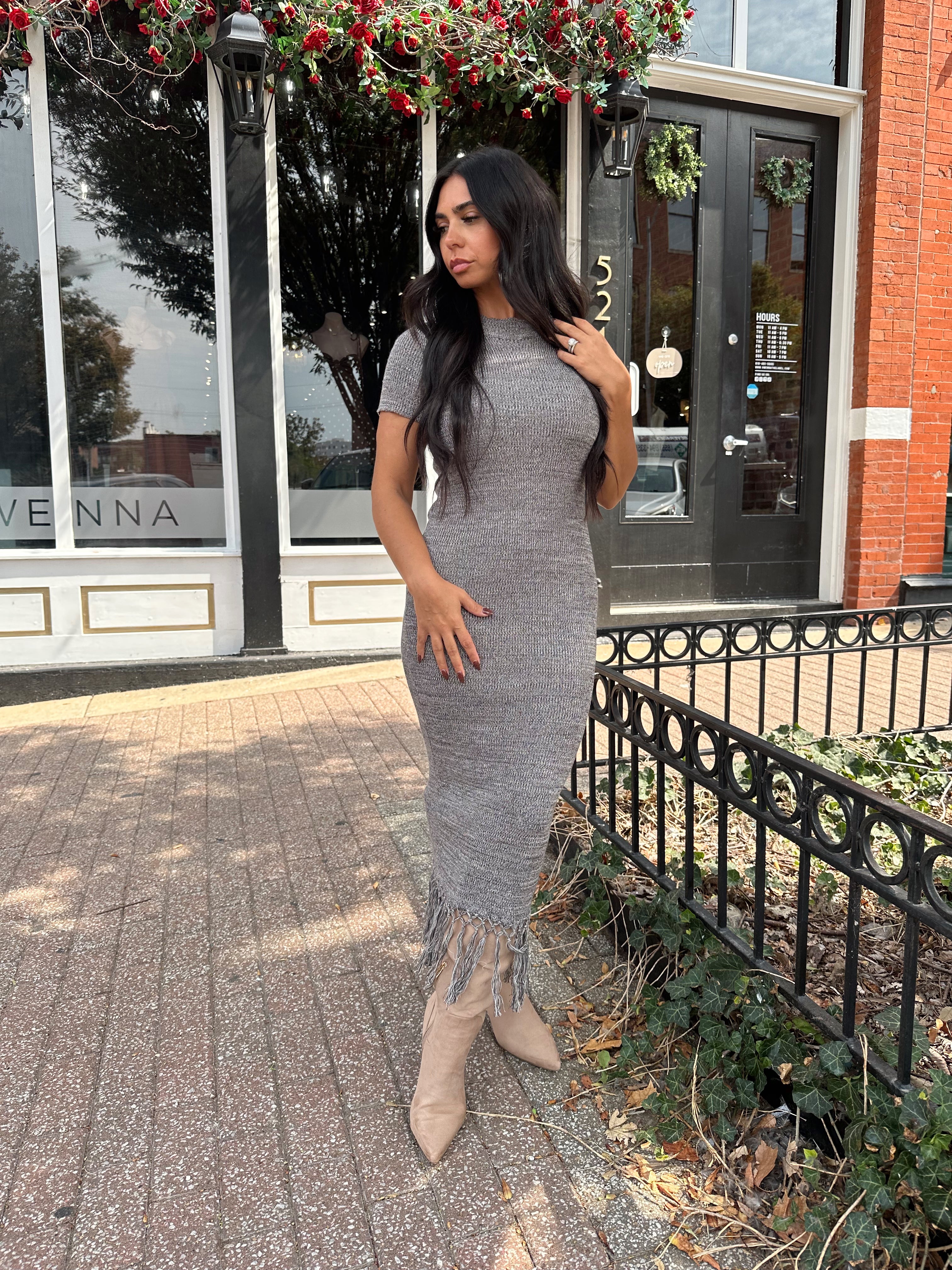 Woman wearing charcoal grey midi dress with fringe hem bottom and short sleeves.