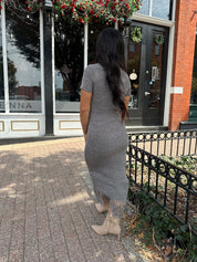 Woman wearing charcoal grey midi dress with fringe hem bottom and short sleeves.