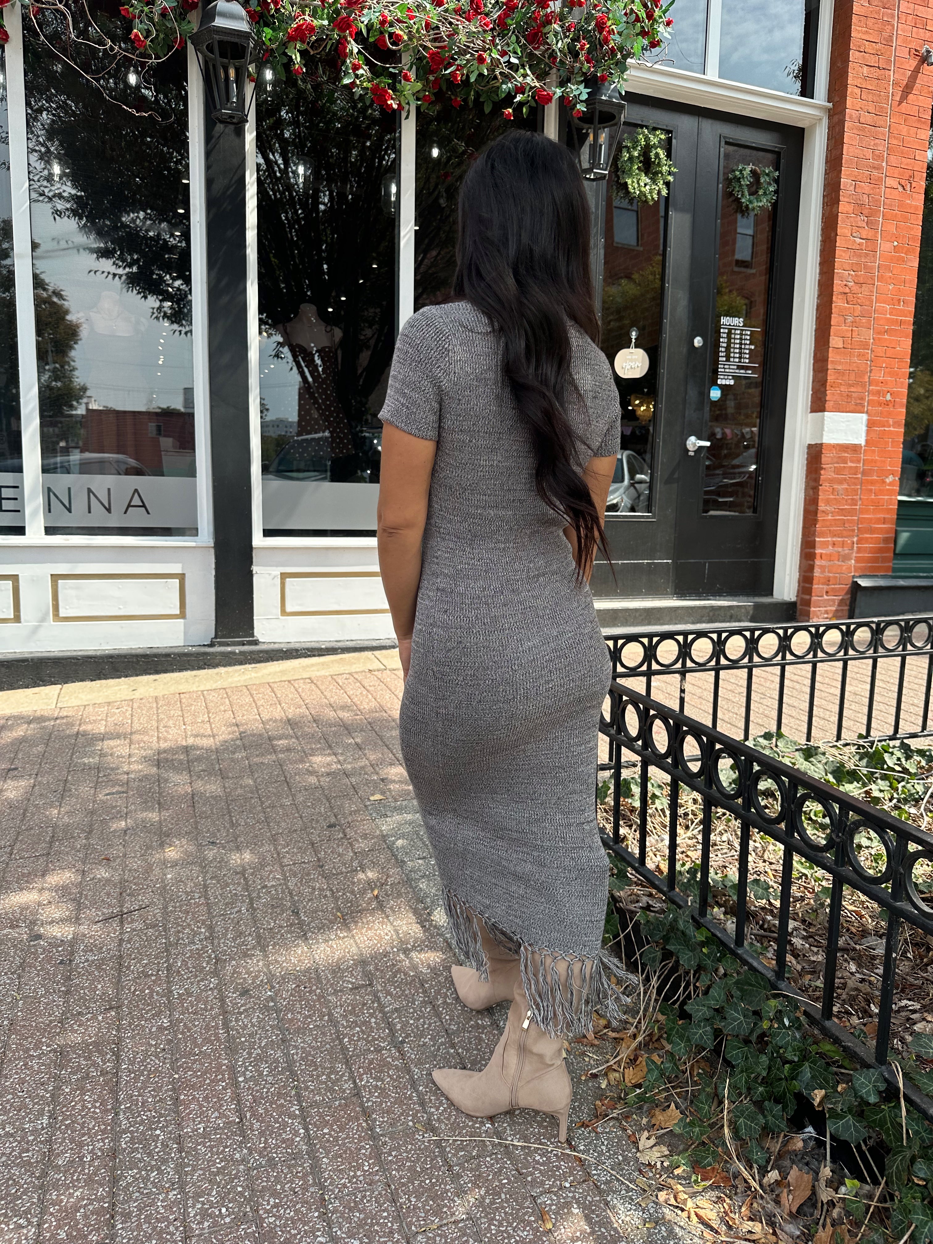 Woman wearing charcoal grey midi dress with fringe hem bottom and short sleeves.
