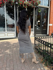 Woman wearing charcoal grey midi dress with fringe hem bottom and short sleeves.
