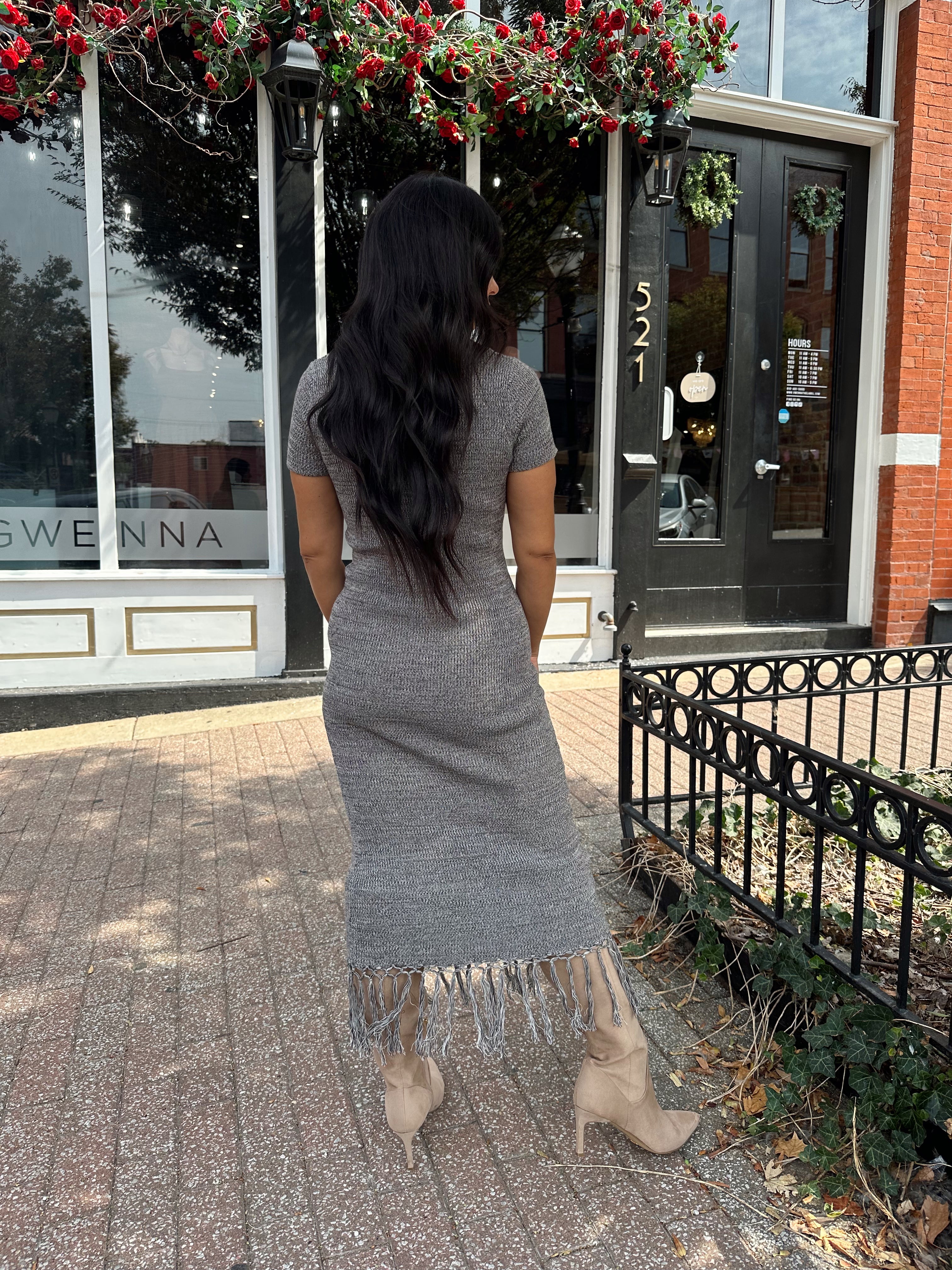 Woman wearing charcoal grey midi dress with fringe hem bottom and short sleeves.