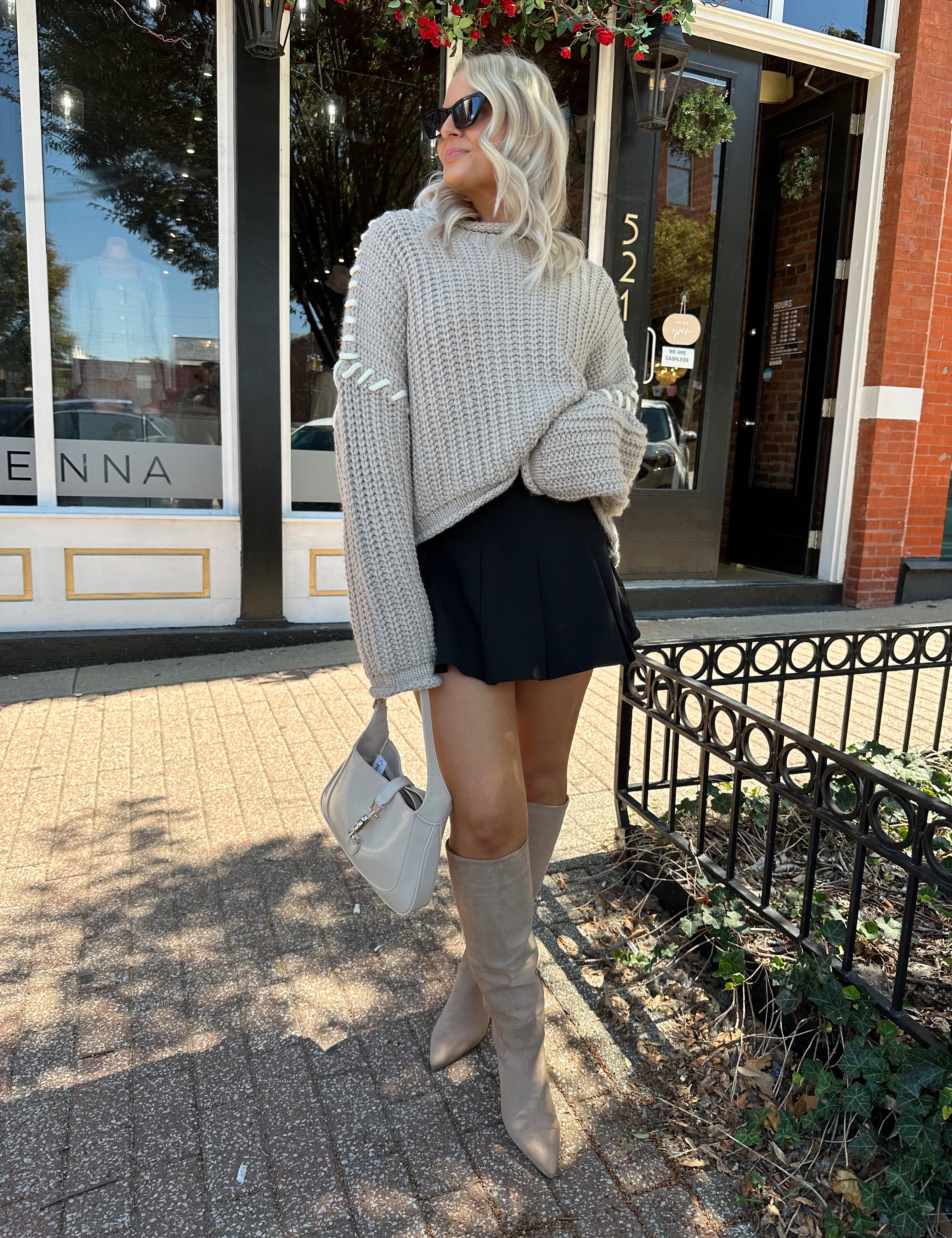 Woman wearing a grey knit oversized sweater with contrast lacing. 