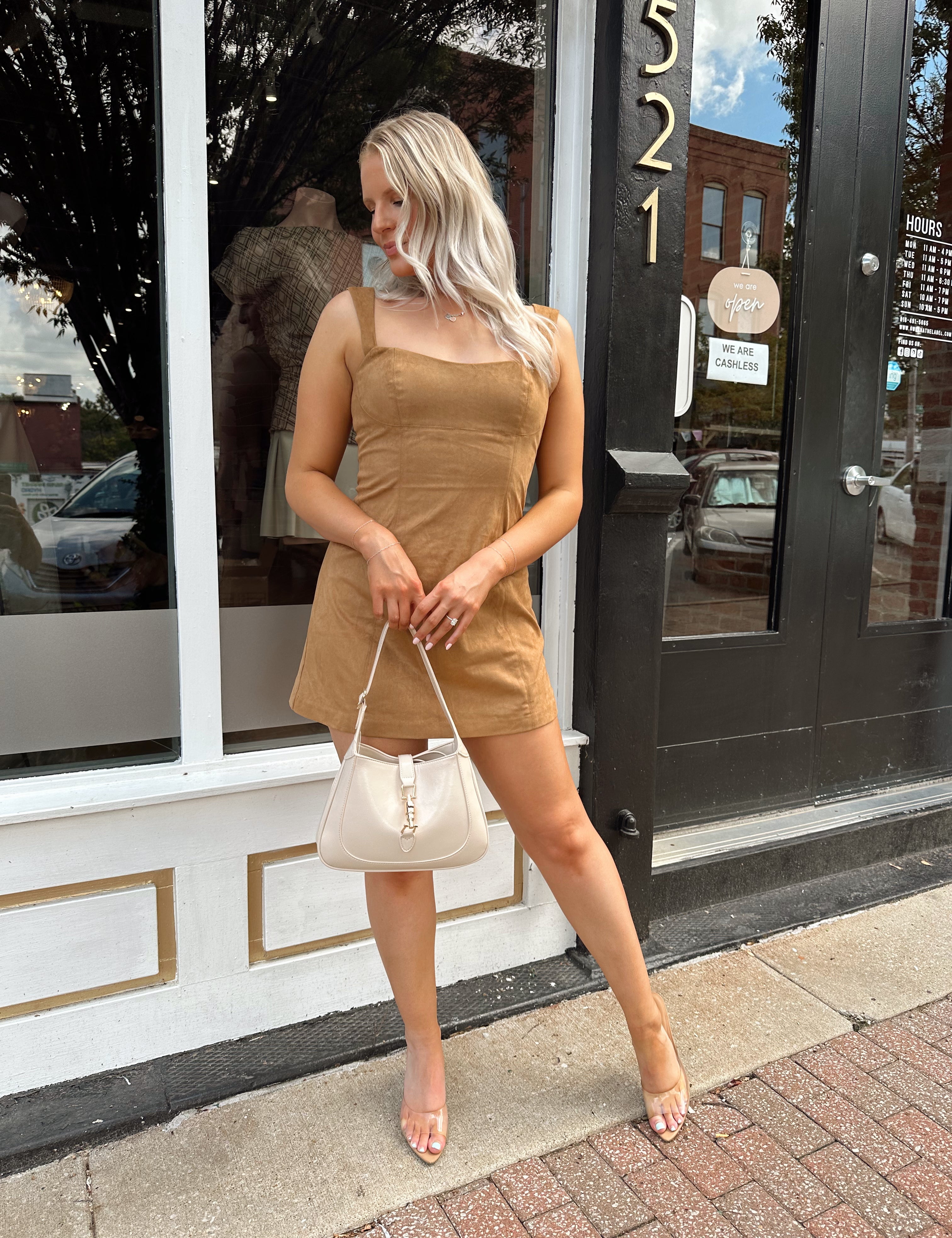 Woman wearing a tan suede sleeveless mini dress with adjustable straps.