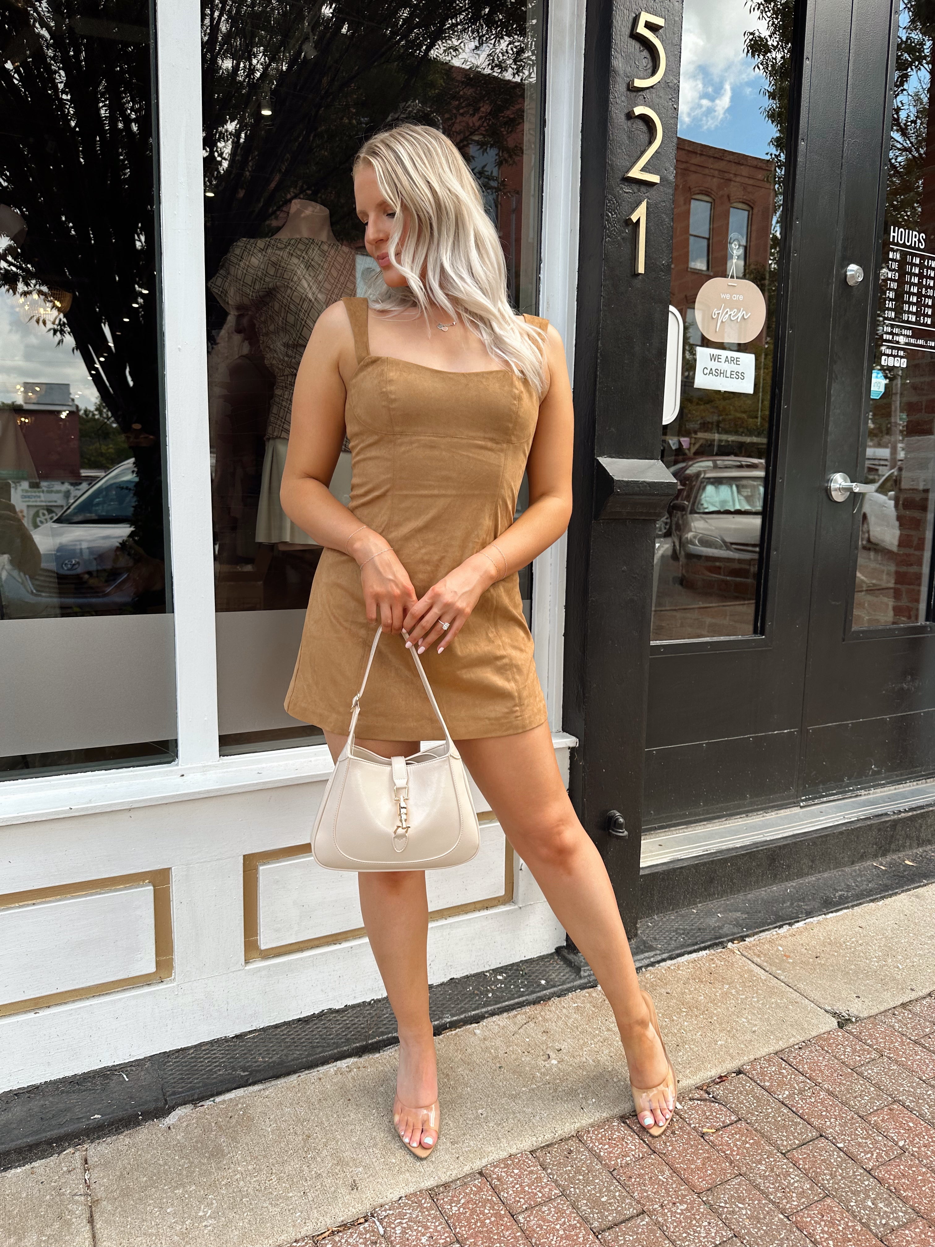 Woman wearing a tan suede sleeveless mini dress with adjustable straps.