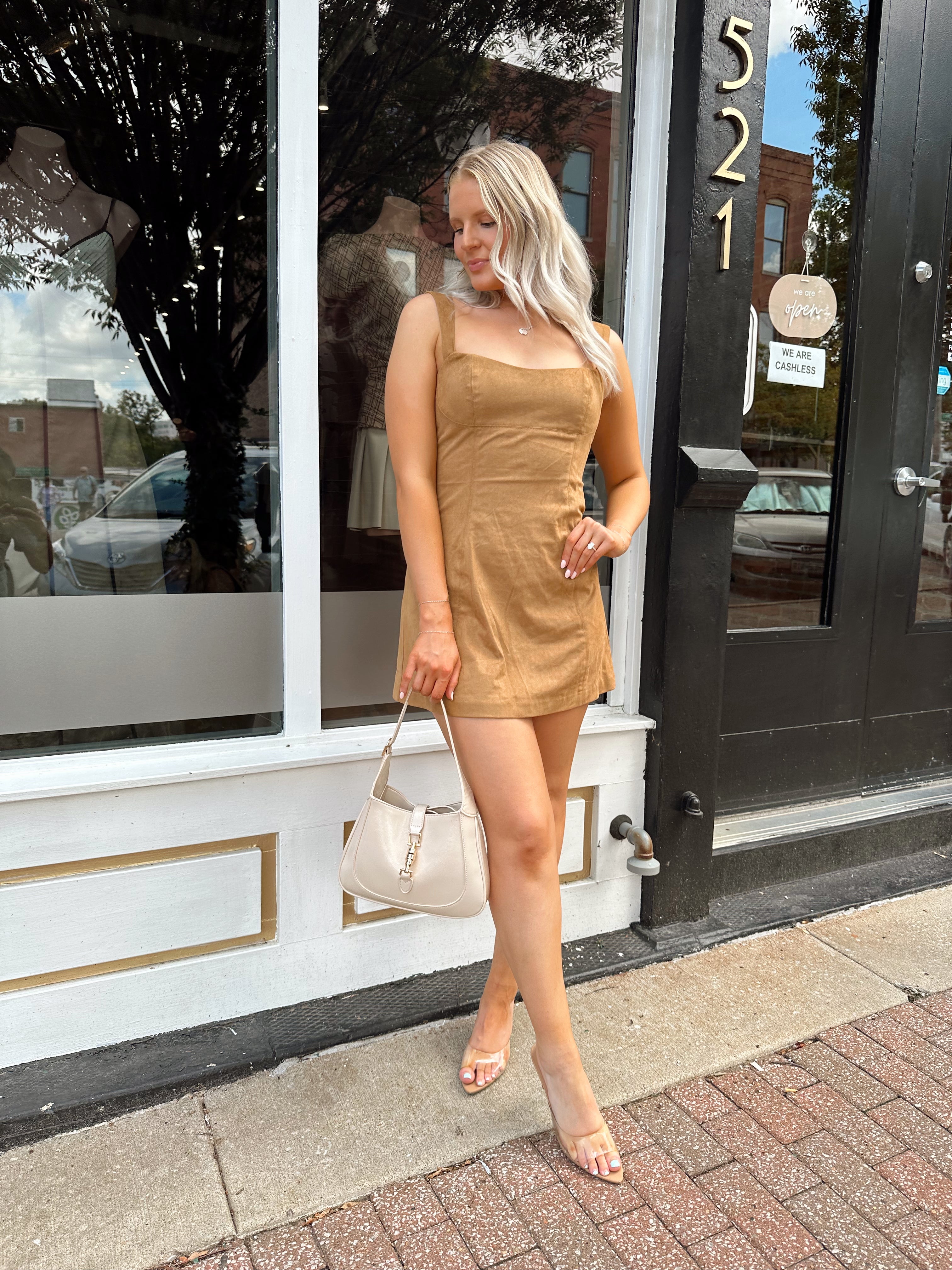 Woman wearing a tan suede sleeveless mini dress with adjustable straps.