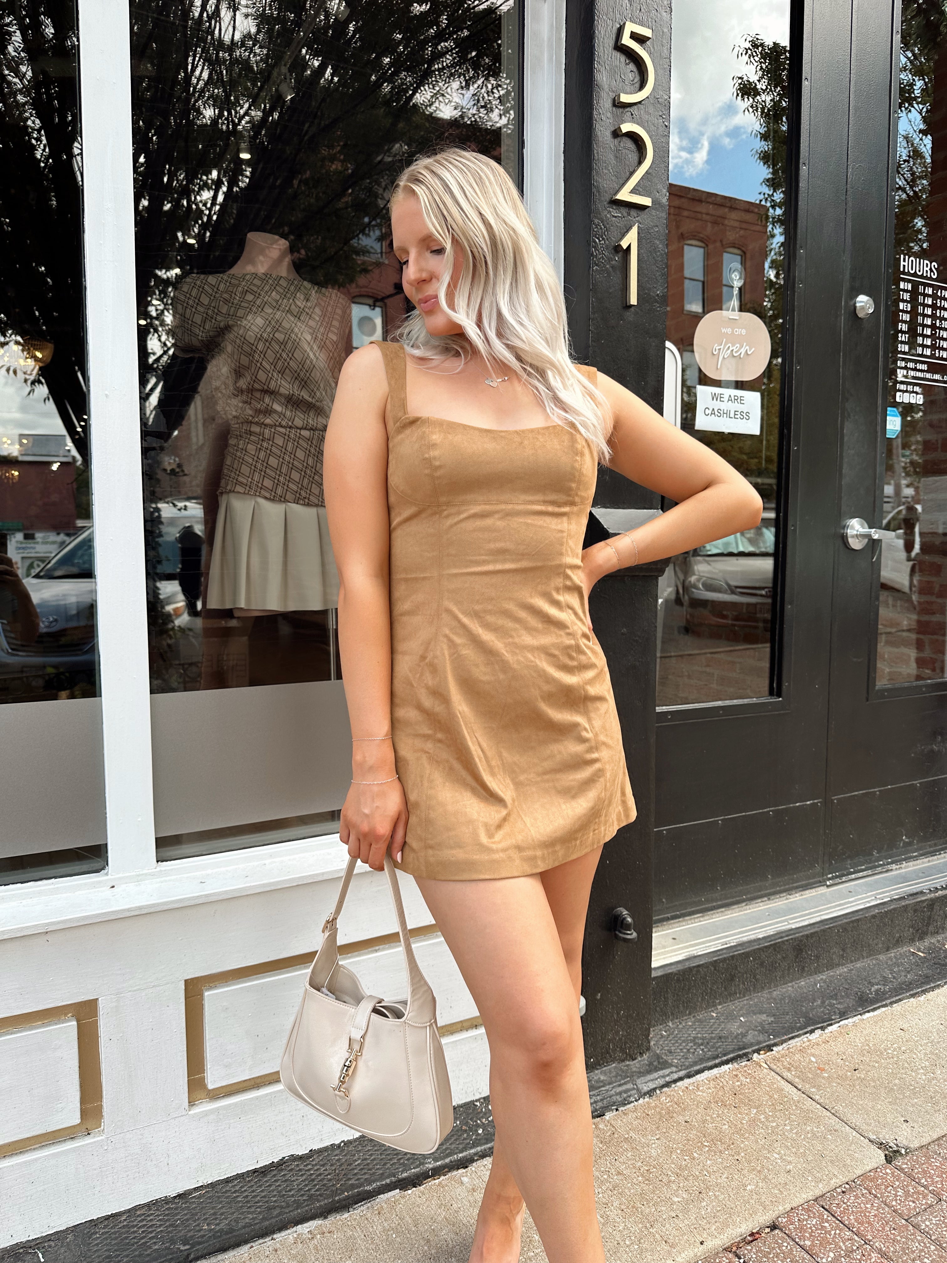 Woman wearing a tan suede sleeveless mini dress with adjustable straps.
