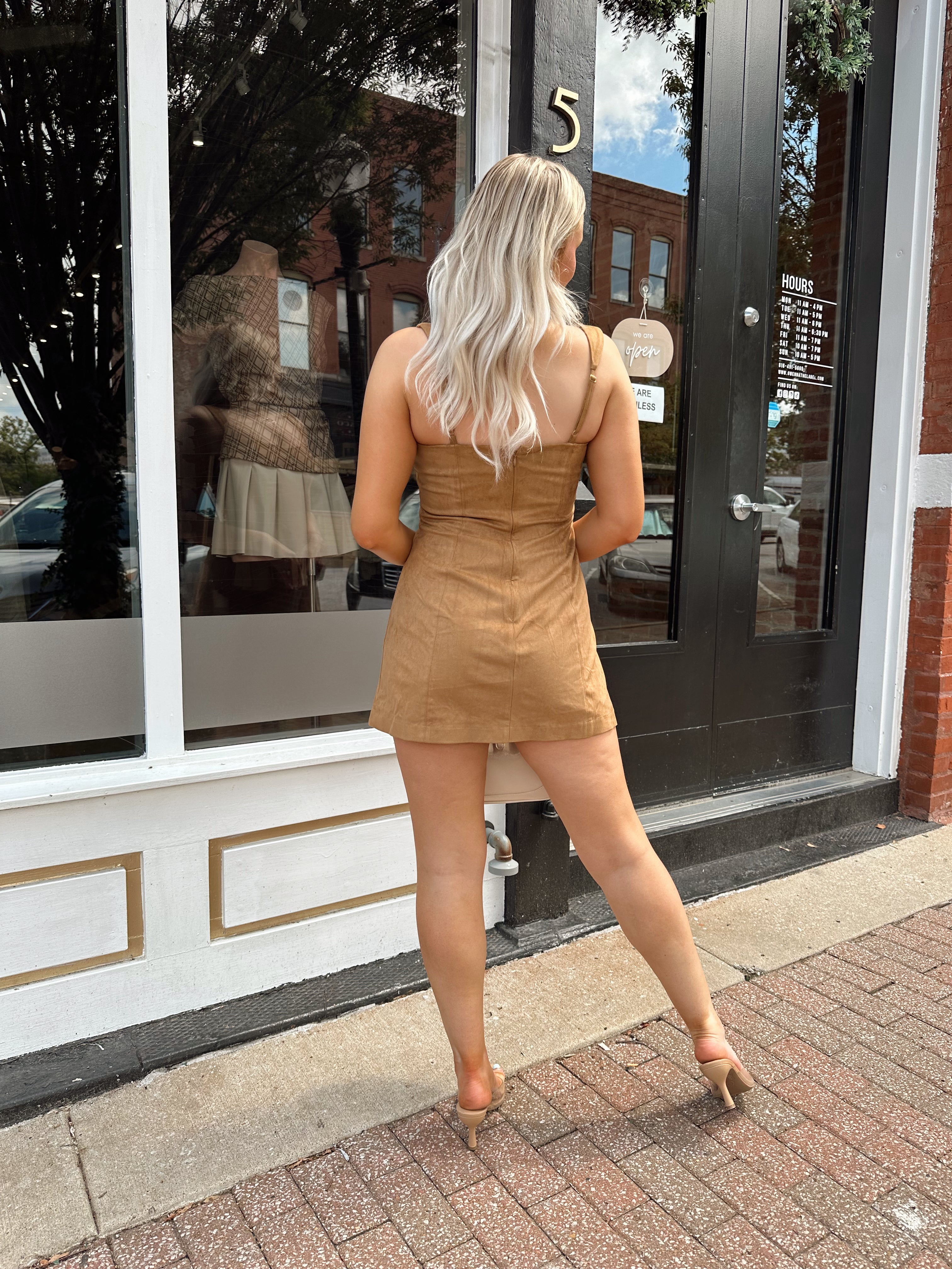 Woman wearing a tan suede sleeveless mini dress with adjustable straps.